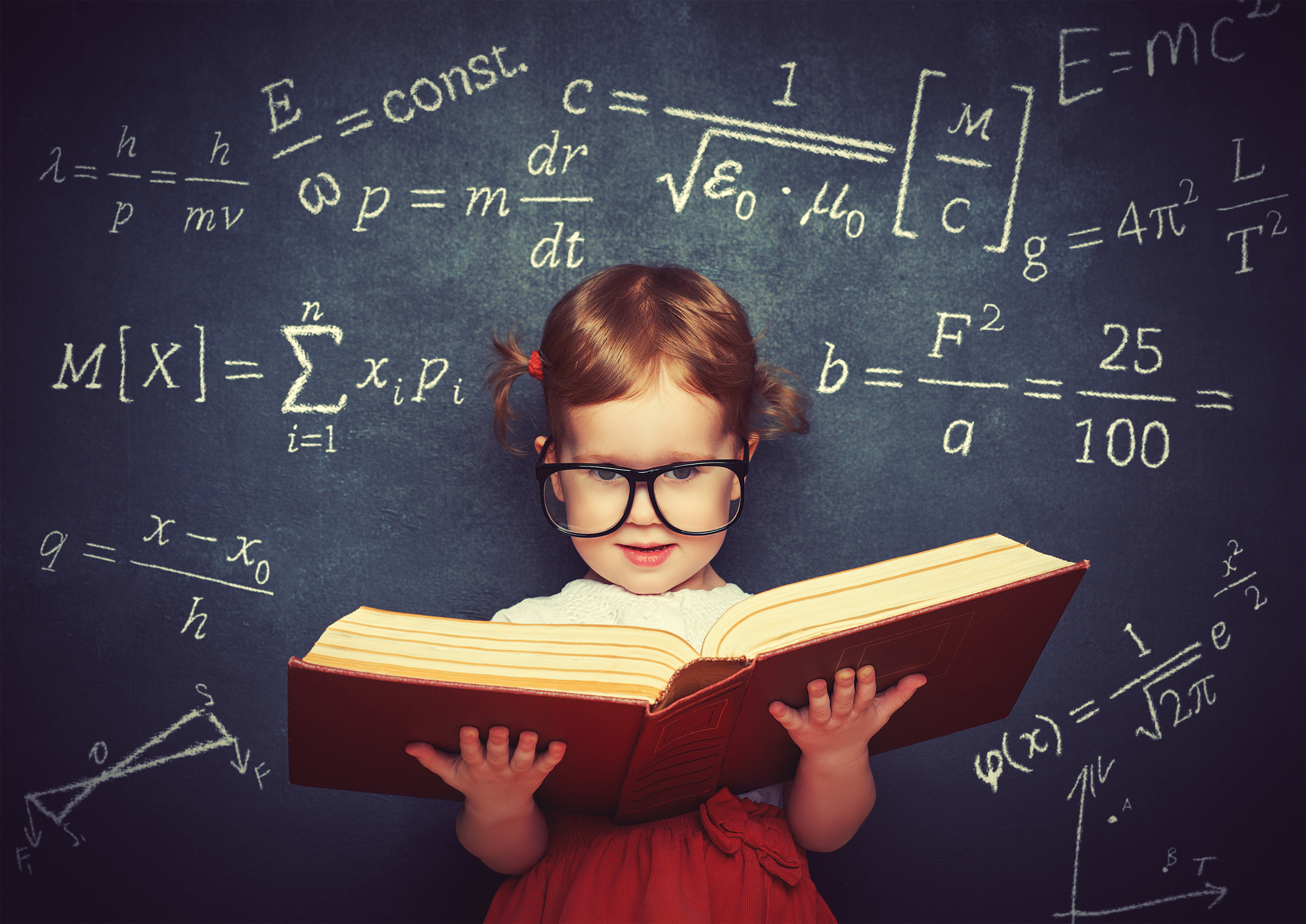 wunderkind little girl schoolgirl with a book from the blackboar