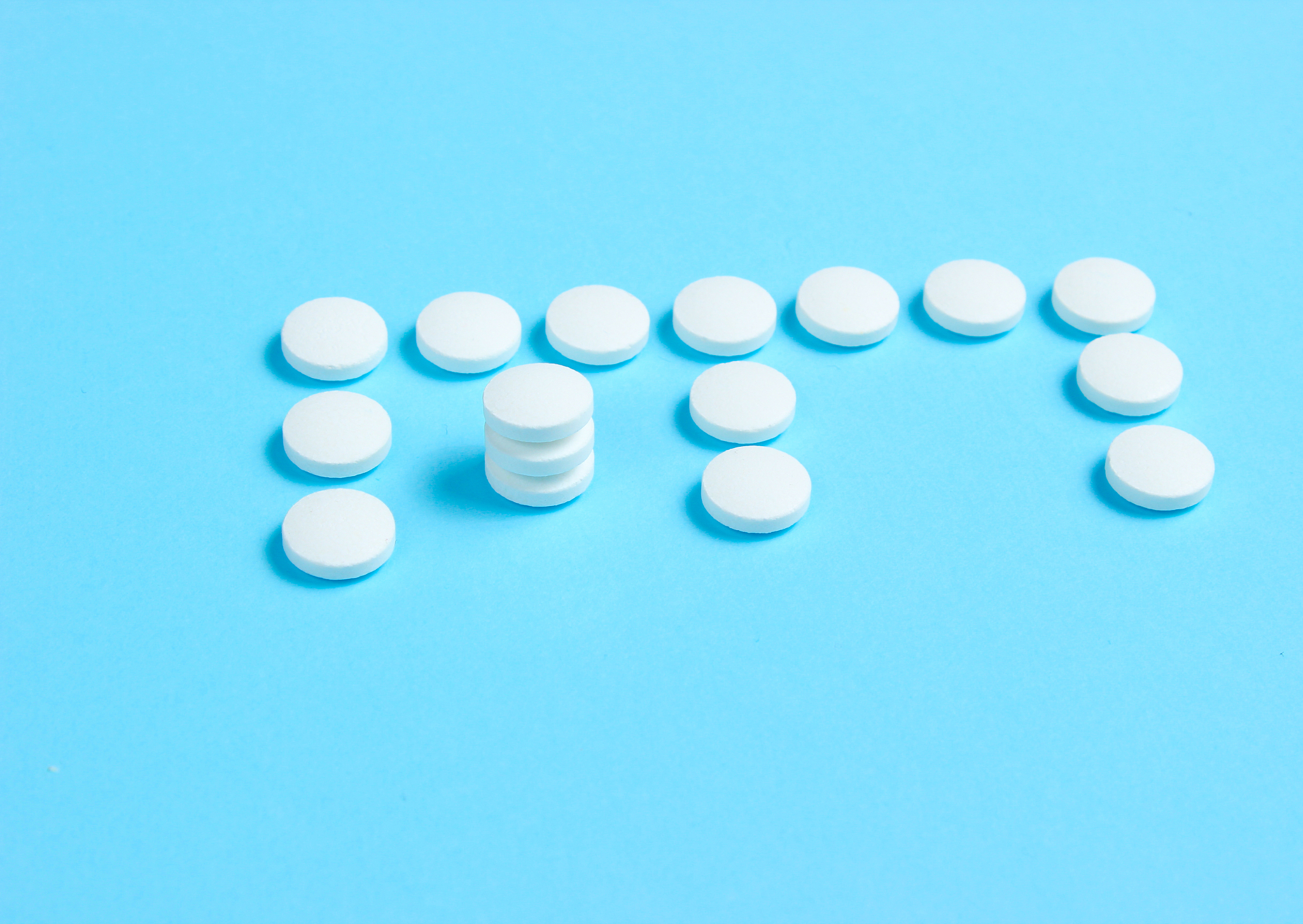 vitamin e. letter e from white pills on blue background. minimal