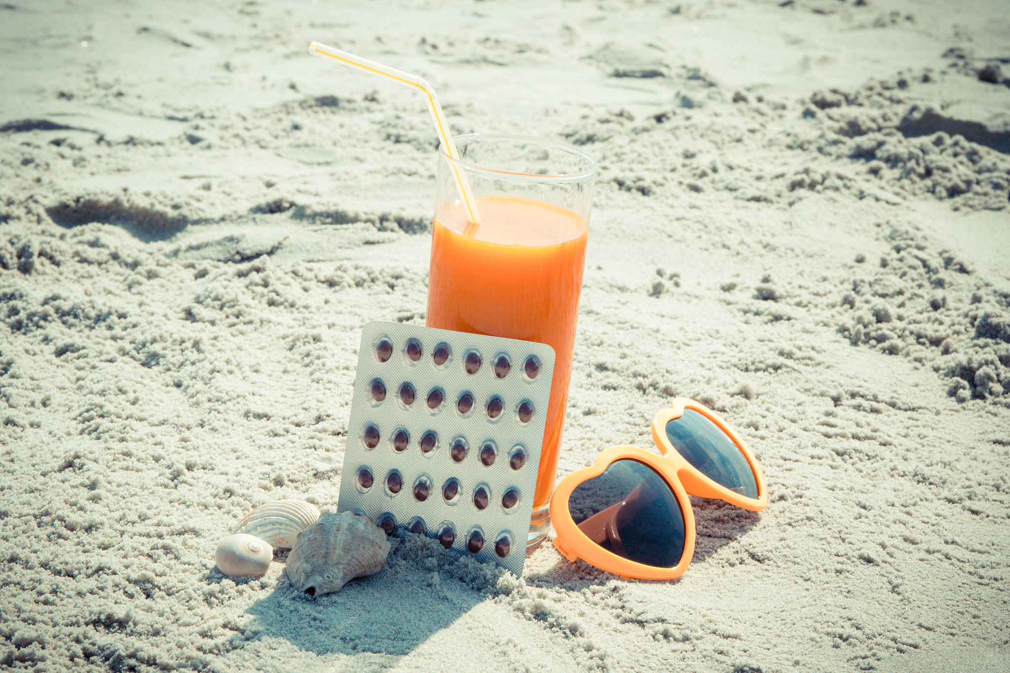 medical pills, carrot juice and sunglasses at beach, concept of 