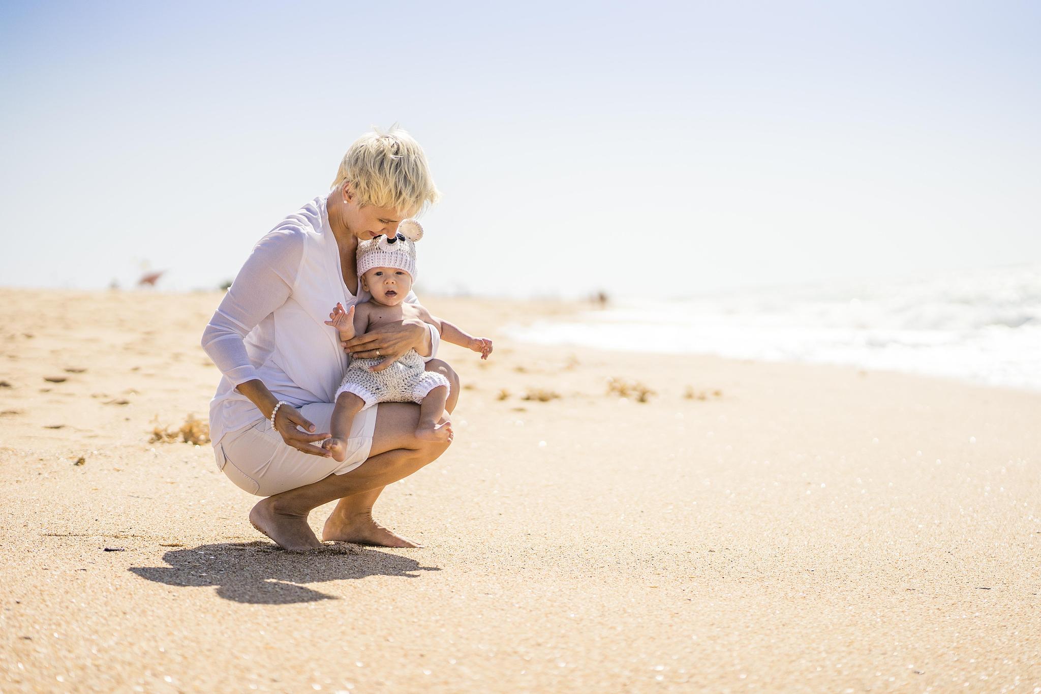 attractive blond mother with 4 months old baby boy on the beach,