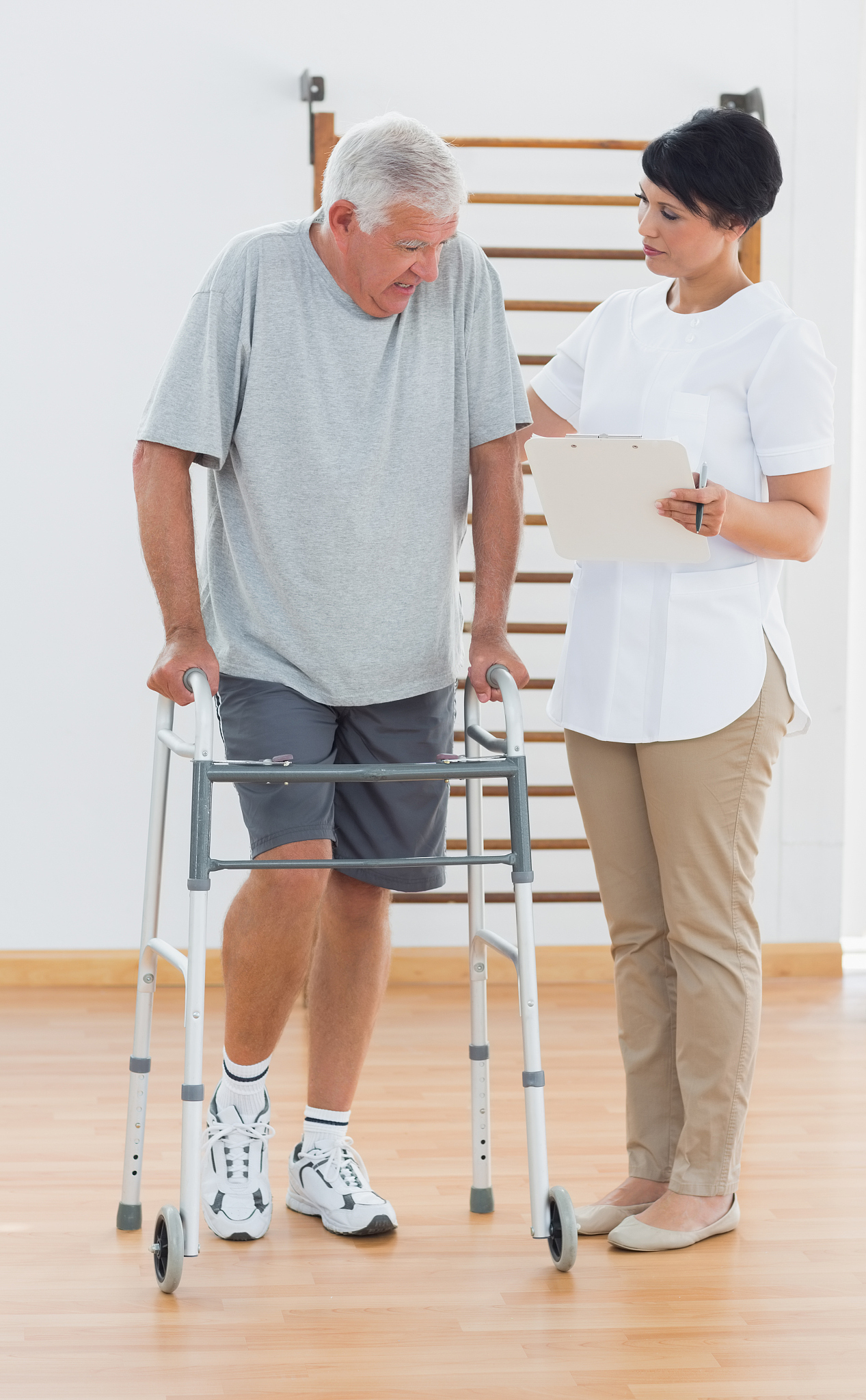 physiotherapist guiding man with walking frame
