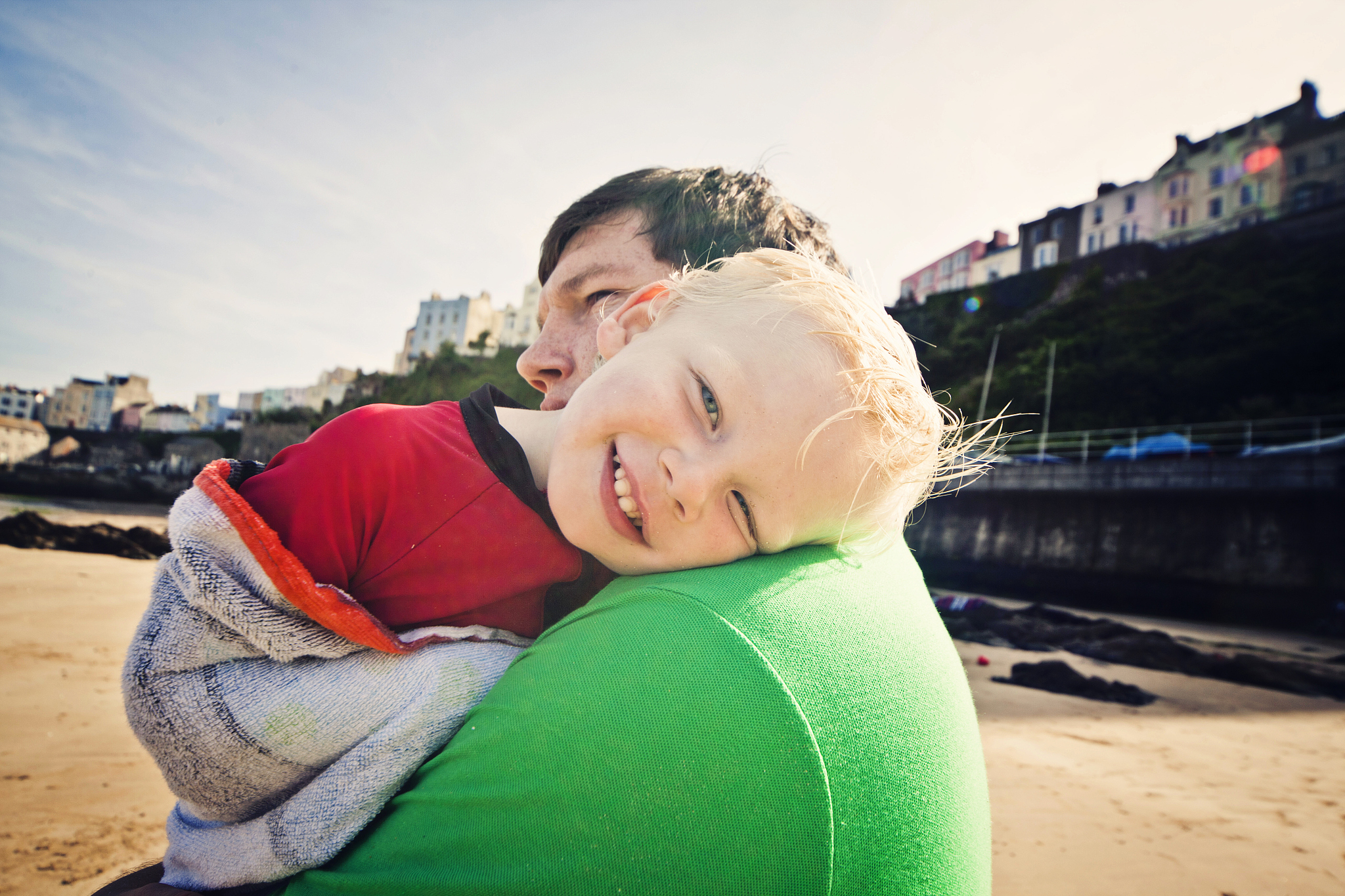 smiling child with his father on the beach.
