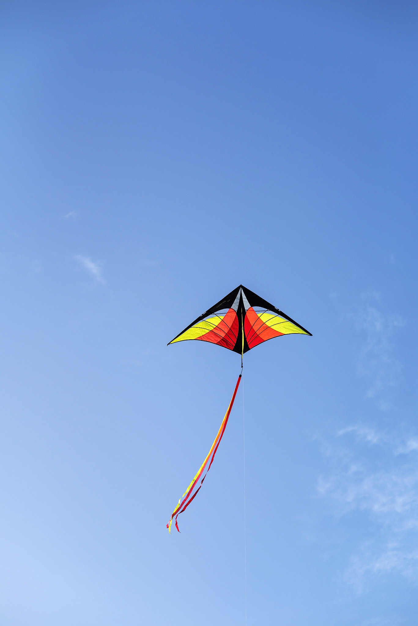 colorful kite is flying in a blue sky