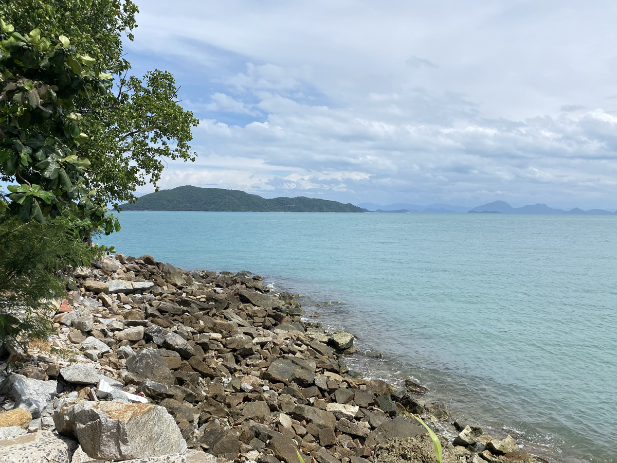 绿松石色的海水拍打着岩石的热带海岸,远方可见岛屿