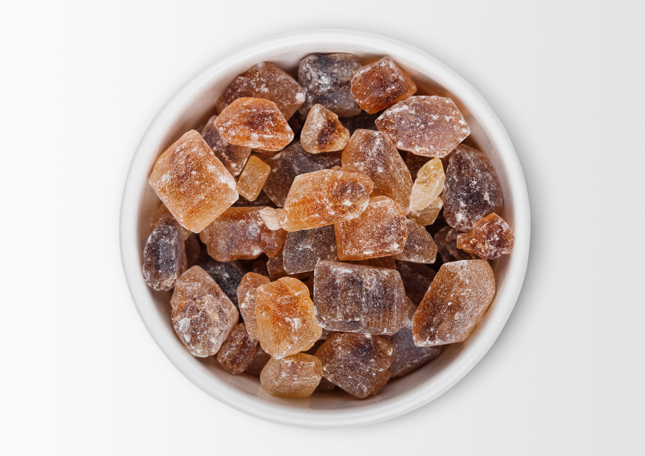 glass bowl of natural brown caramelized sugar cubes on white bac