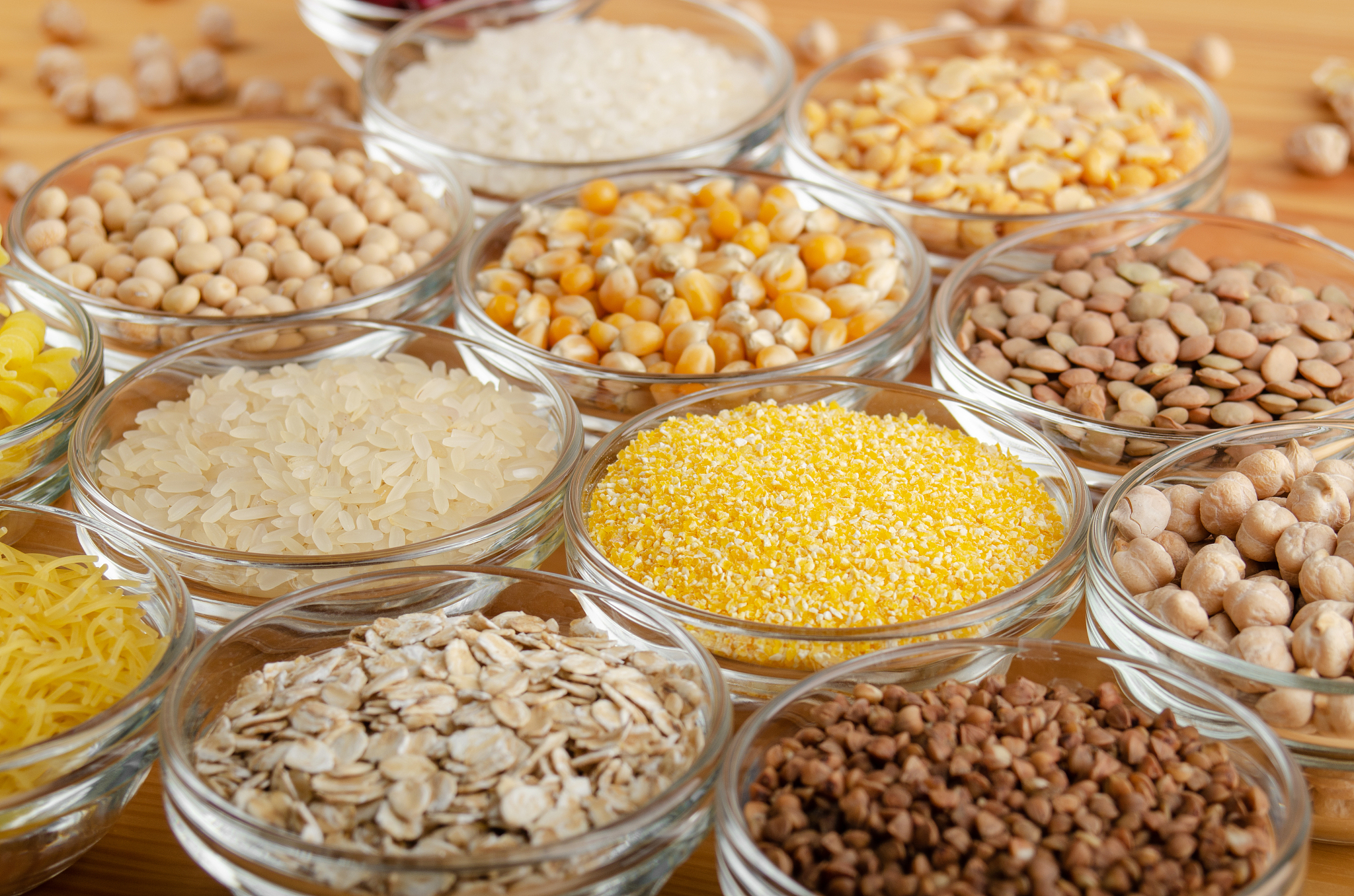 set of various legumes and grains in glass bowls on wooden kitch