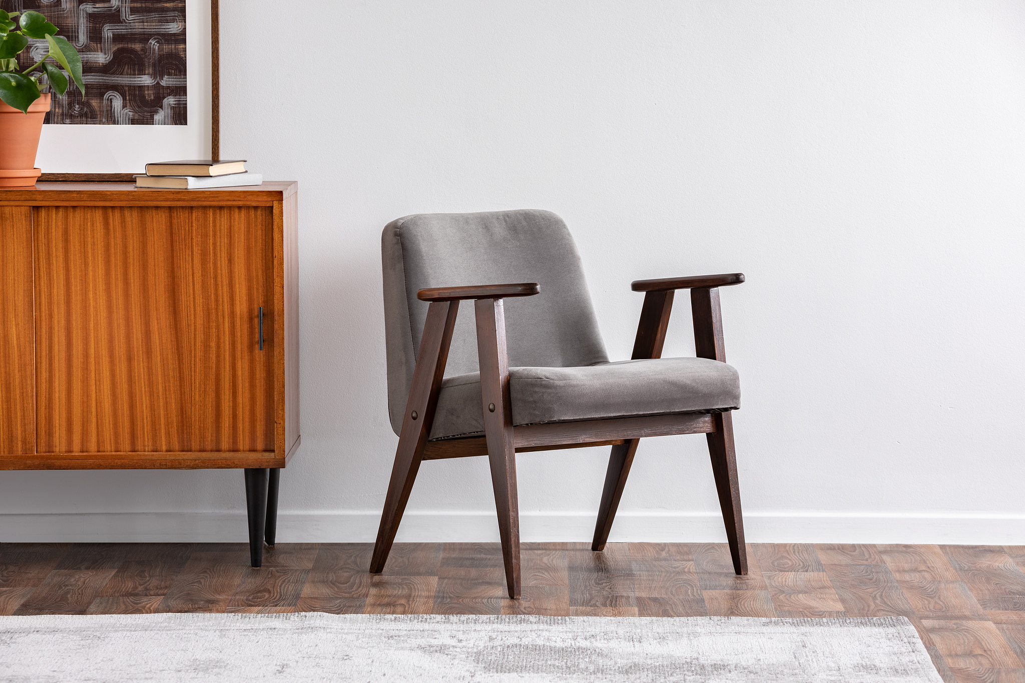 grey armchair next to wooden cabinet with plant in grey retro li