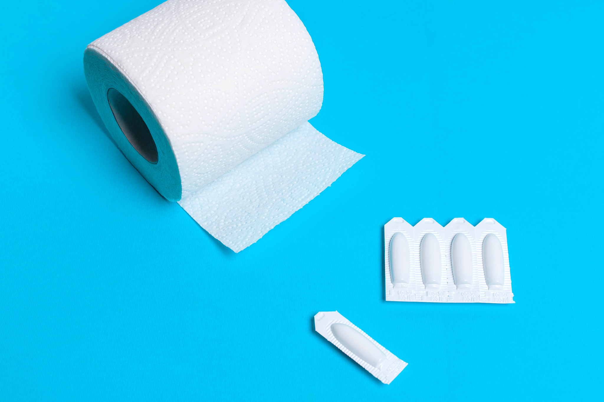 suppository and toilet paper on a blue background, for the treat