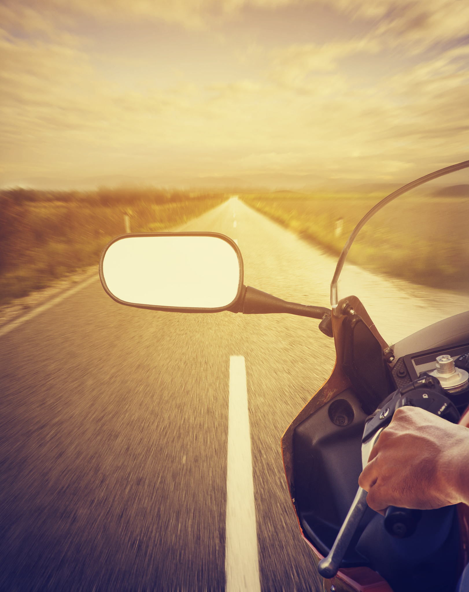 cropped image of person riding motorcycle on road during sunset