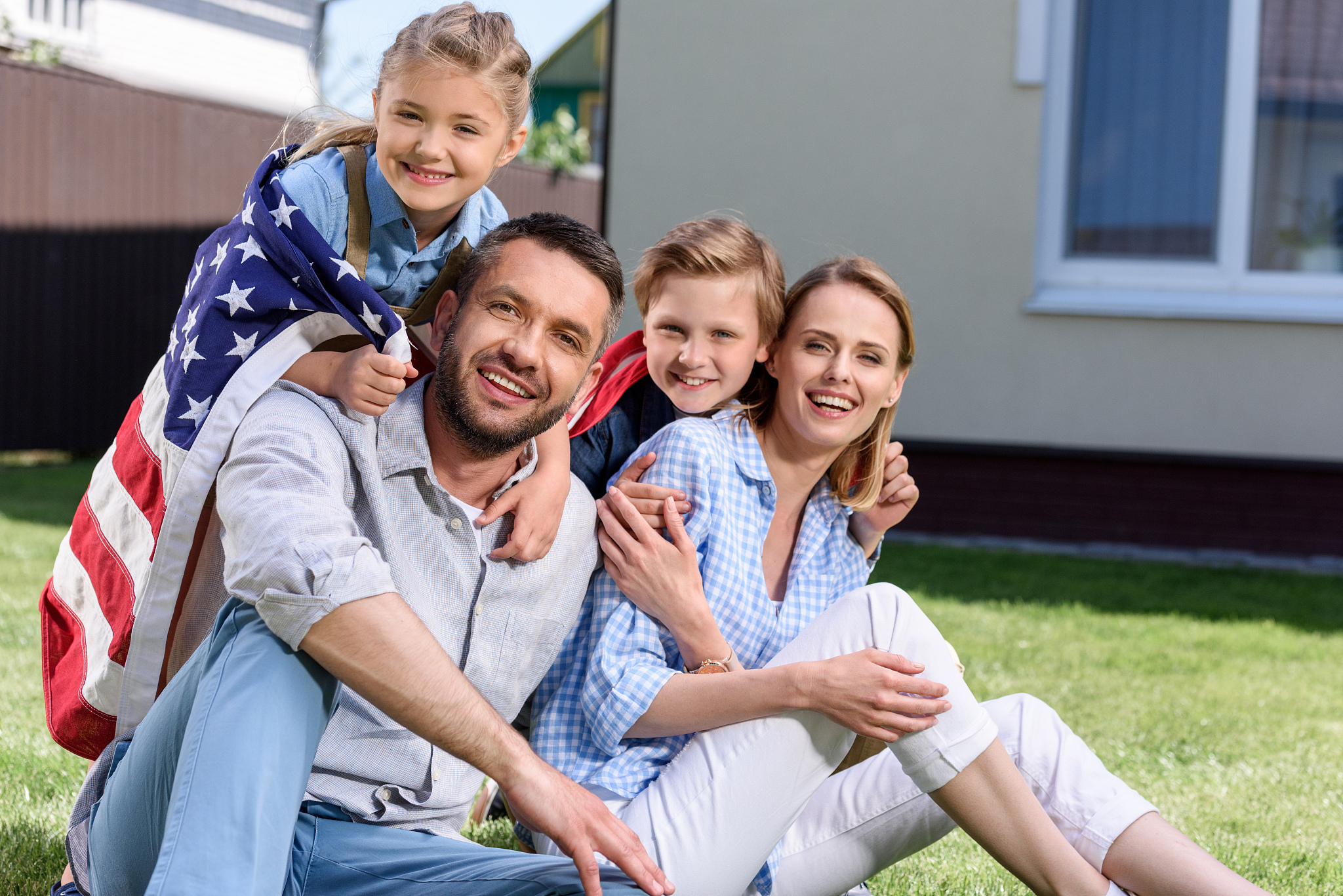 happy family with american flag hugging outdoors, independence d