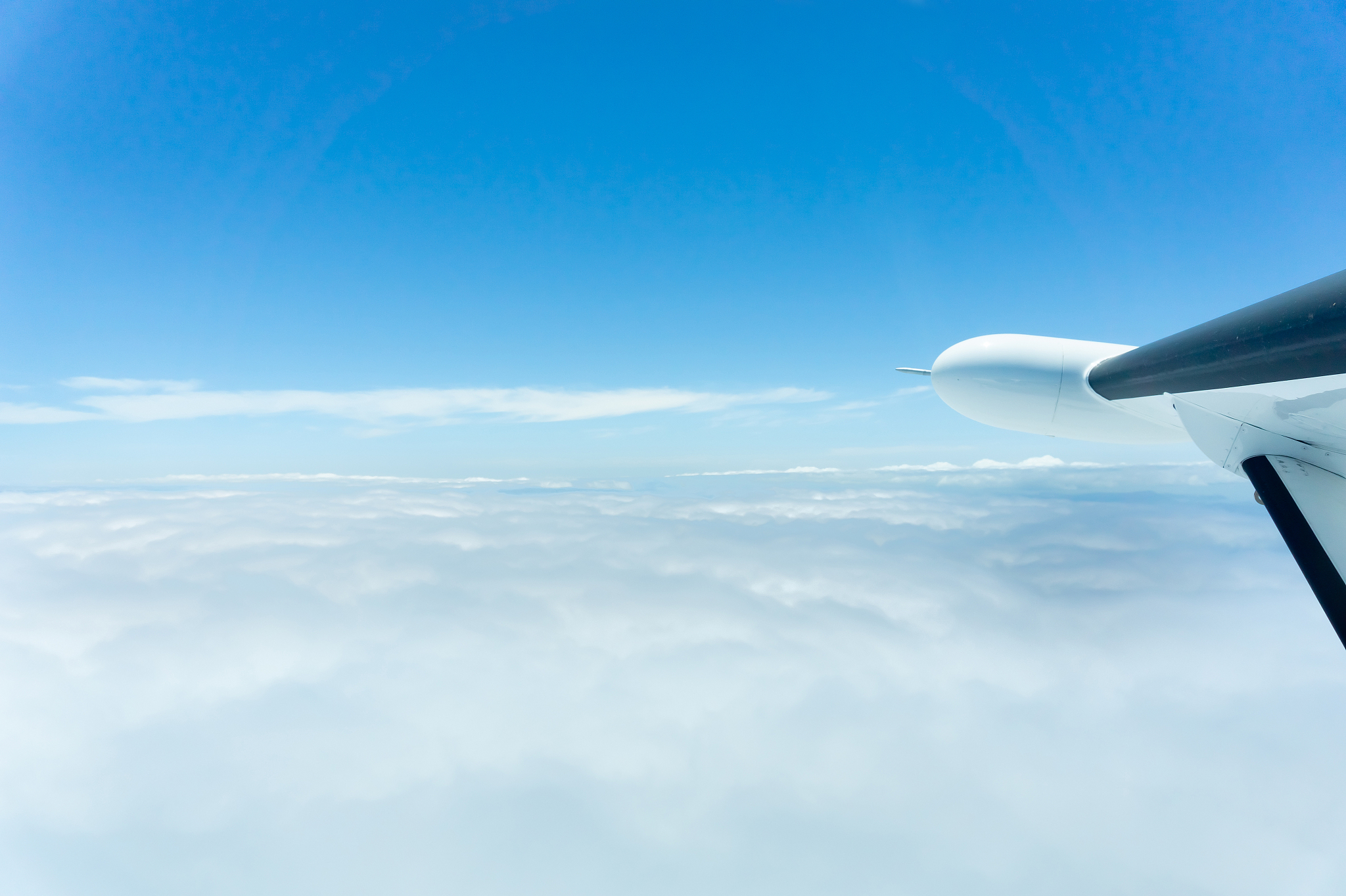 through window of small plane flying above clouds,