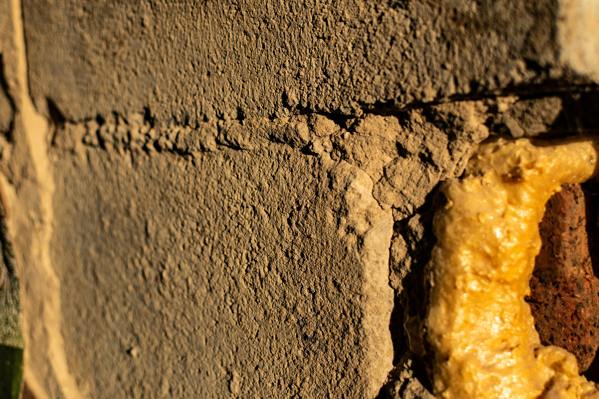 the cemented wall is grey and brown with texture and relief, the
