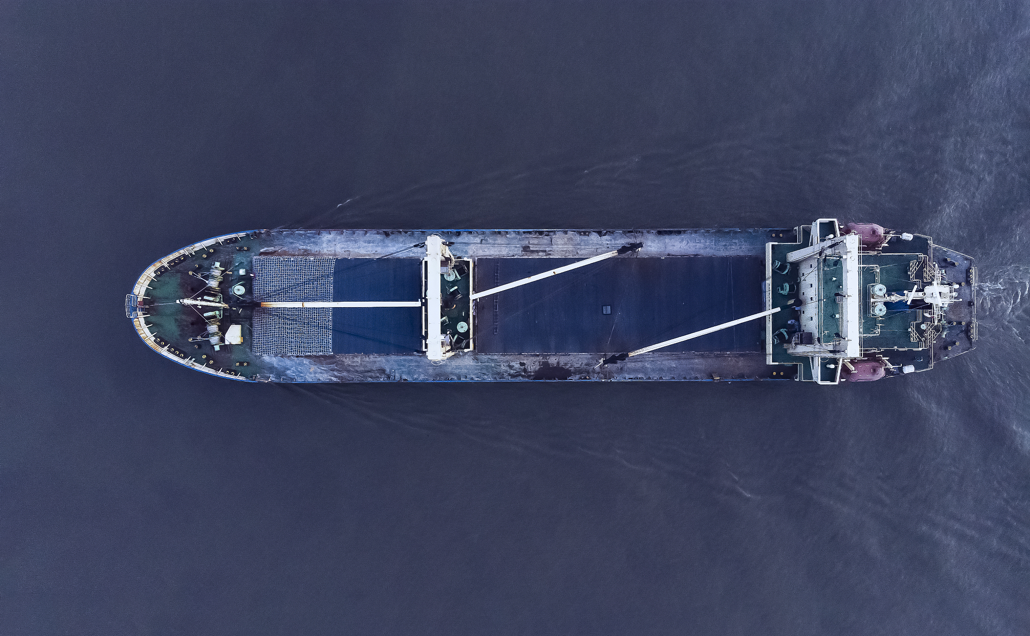 a large cargo ship with a heliport running in the sea