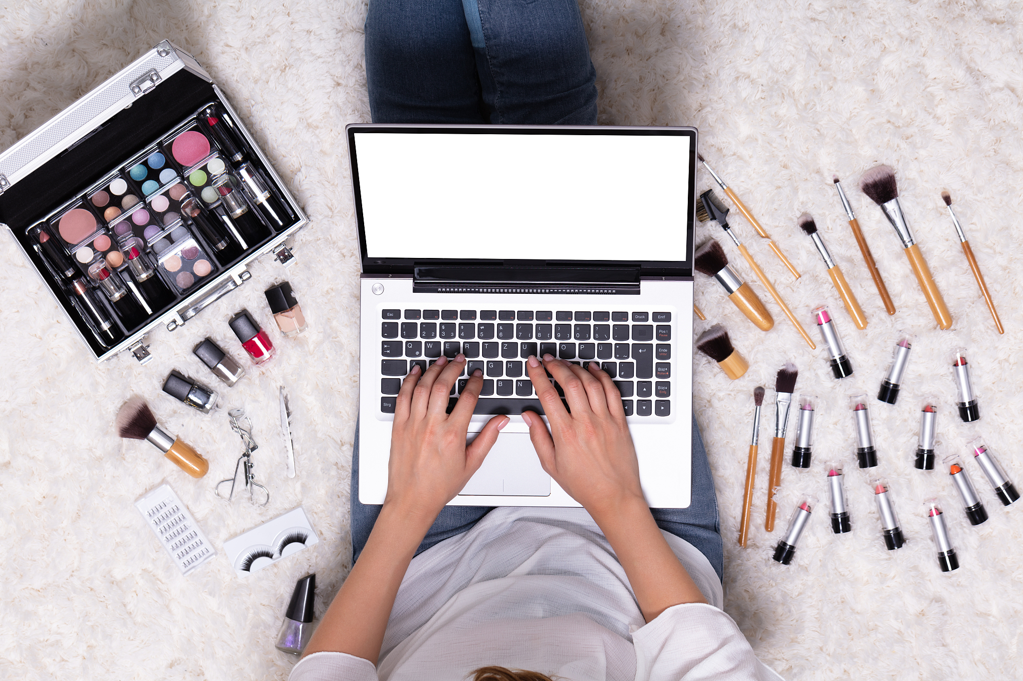 woman using laptop surrounded by cosmetic product