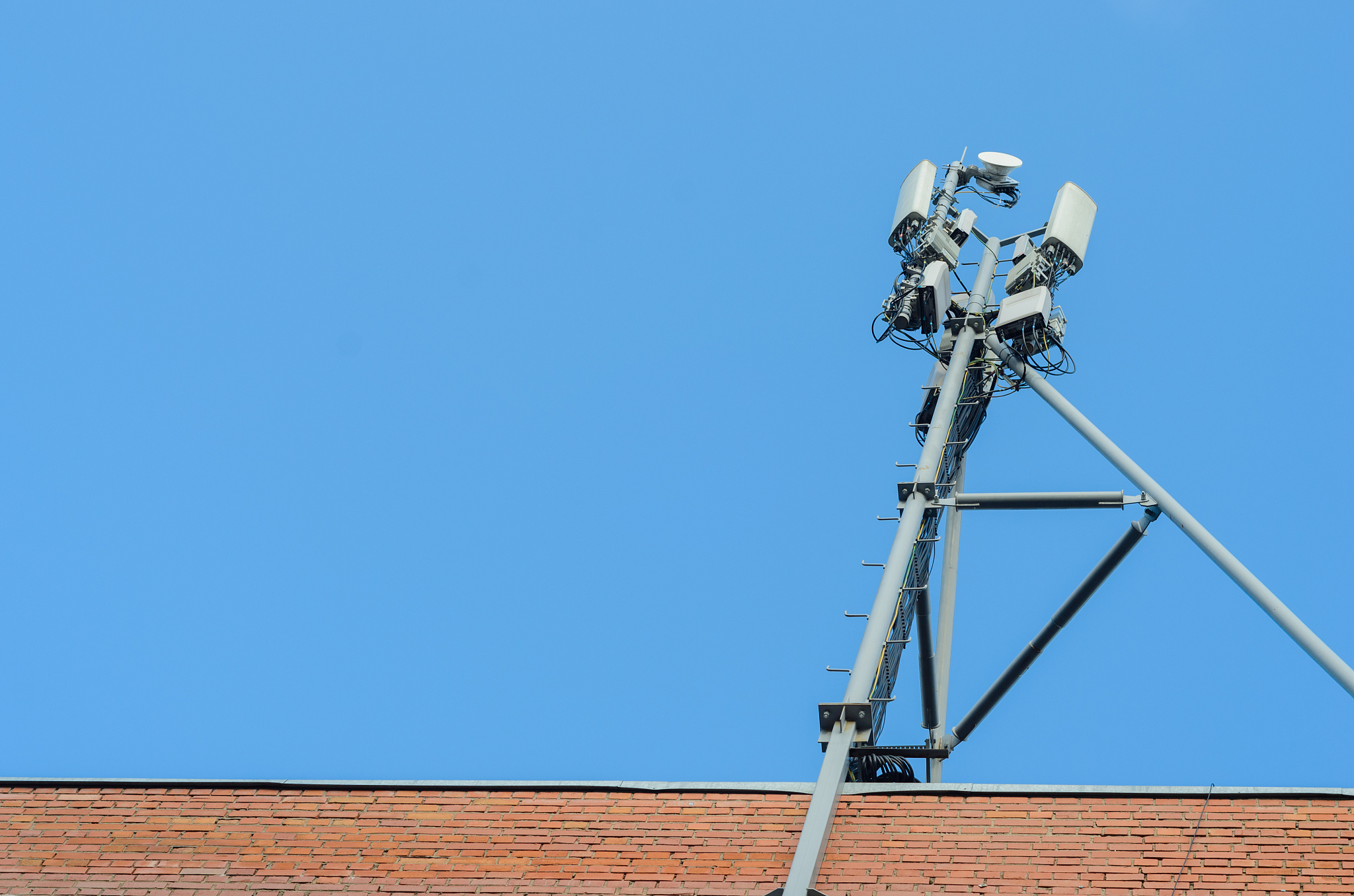 cellular antenna on the roof of a brick house on blue sky backgr
