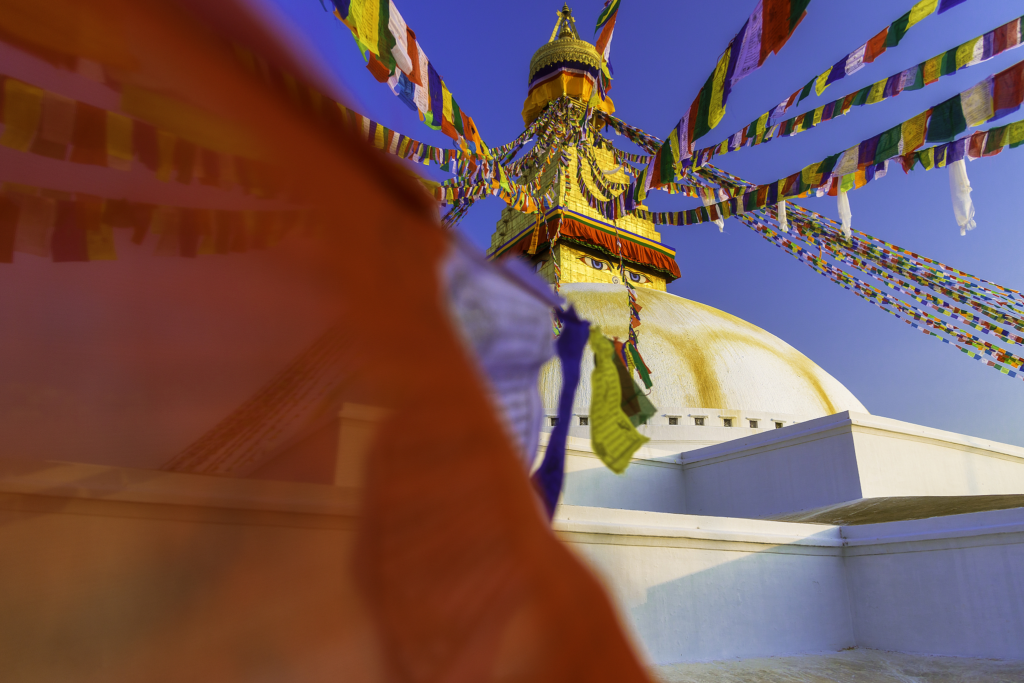 the boudhanath stupa with prayer flag in foreground, nepal.