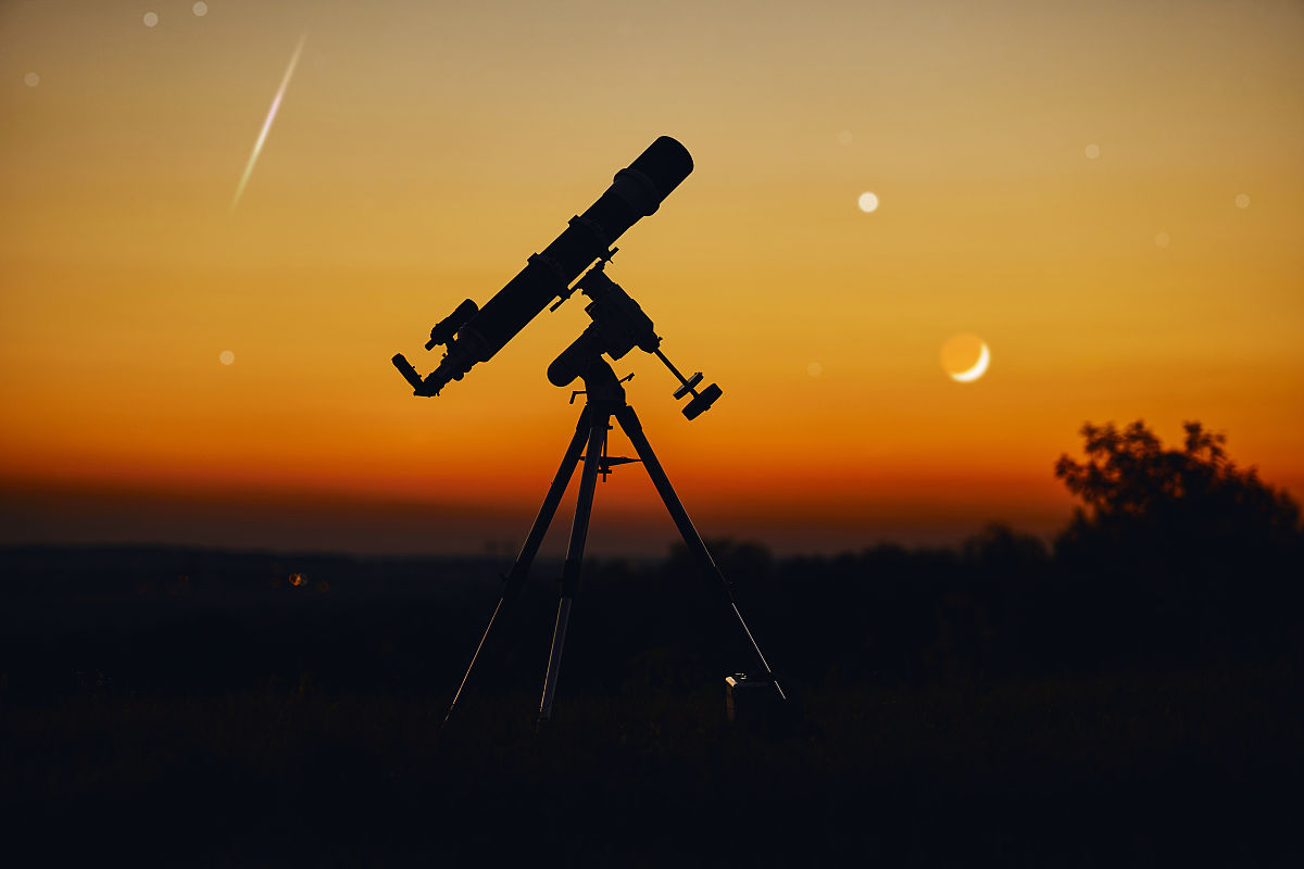 望远镜的剪影和星空下的乡村.