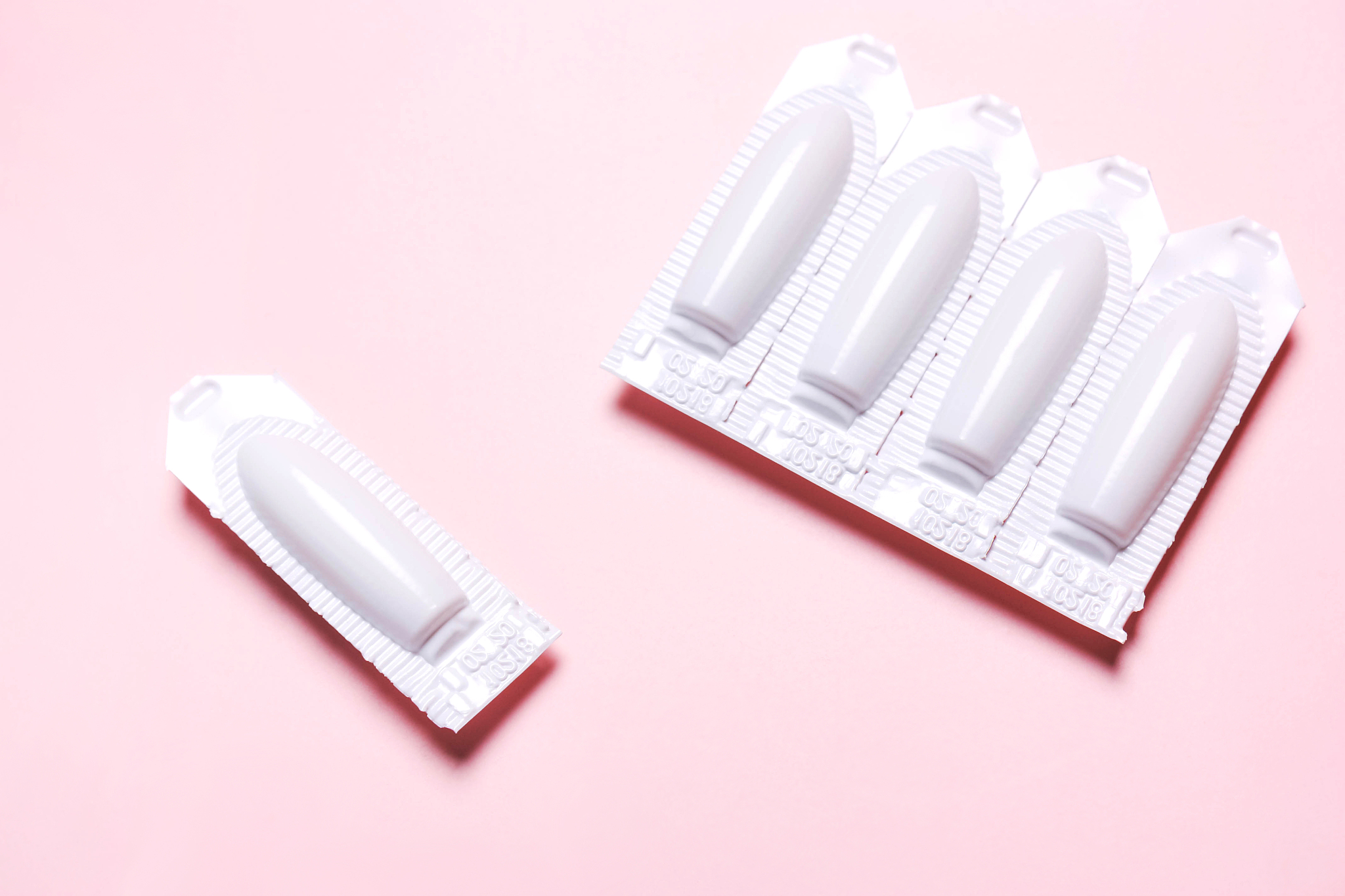 suppository on a pink background, for the treatment of hemorrhoi