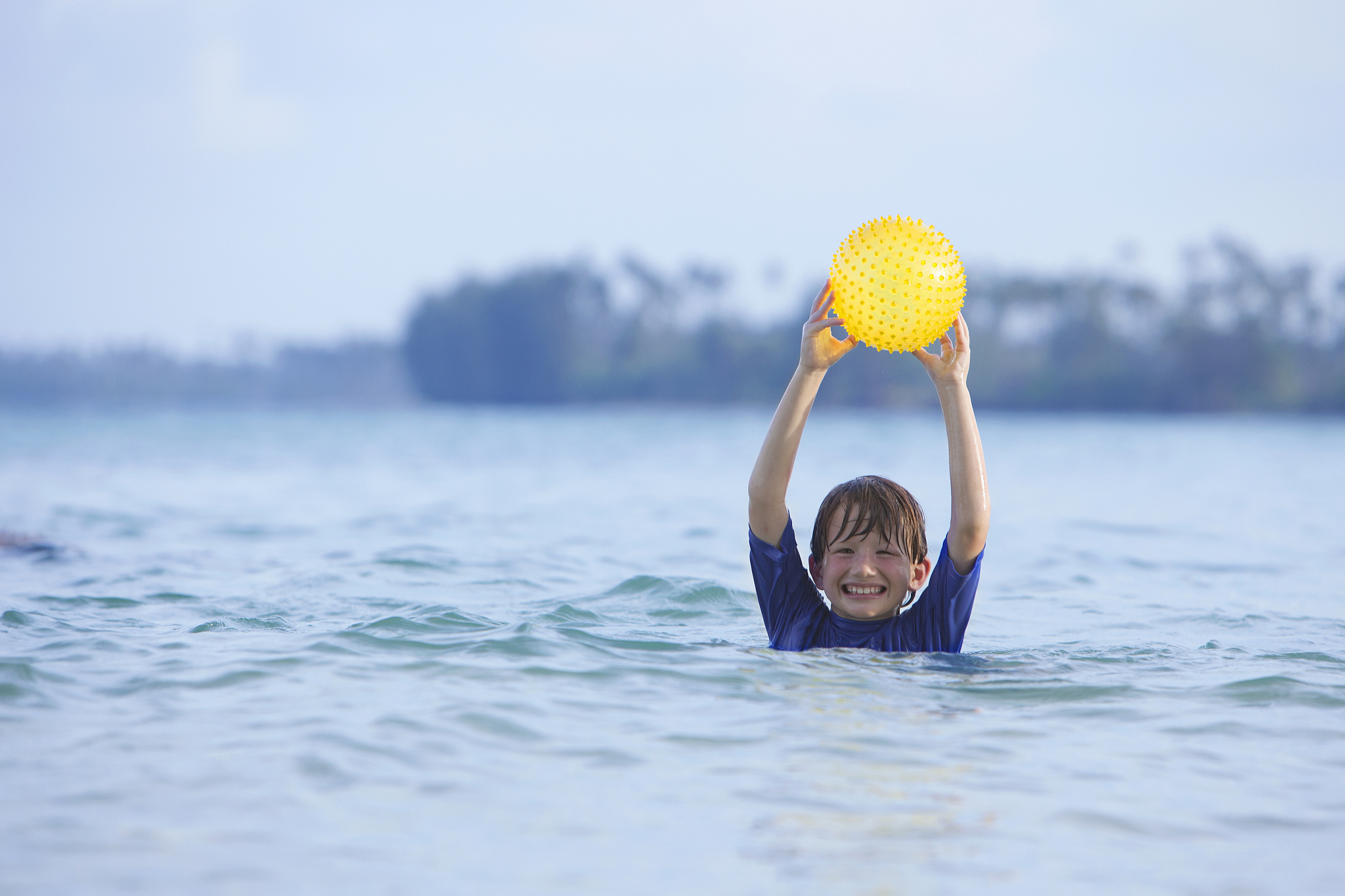 young boy holding a ball in the sea