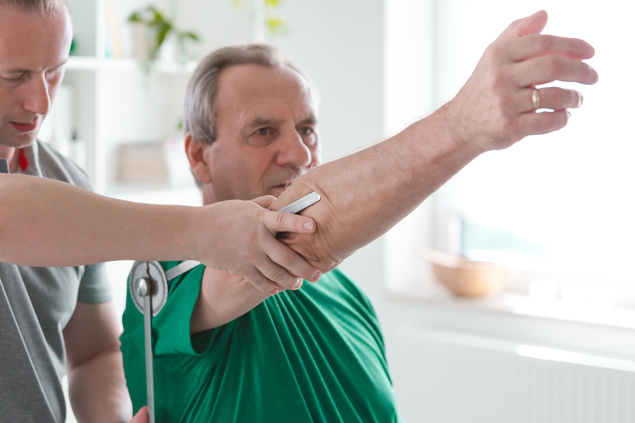 physiotherapist examining patient's sholuder with goniometer