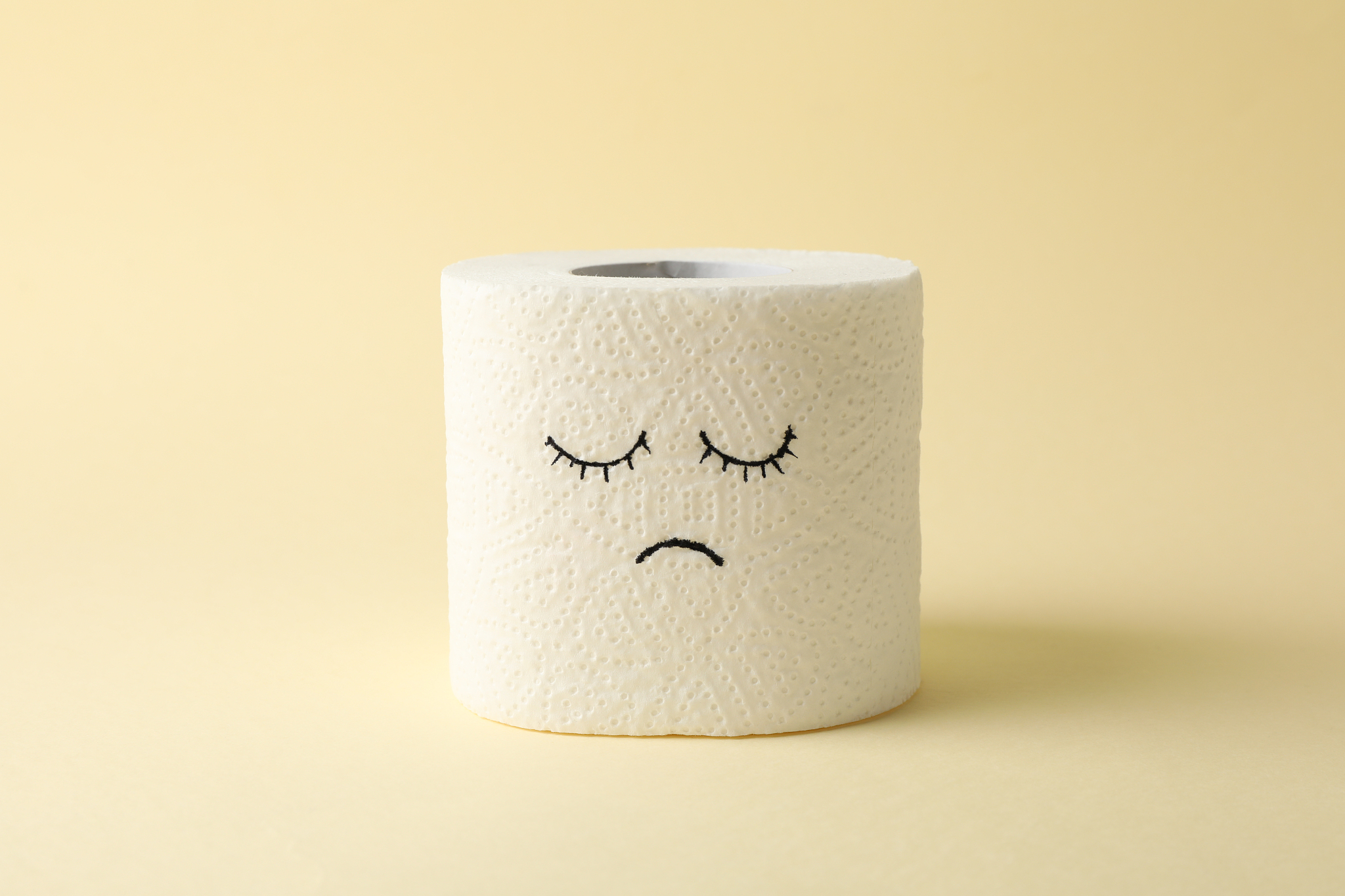 toilet paper with sad face on beige background