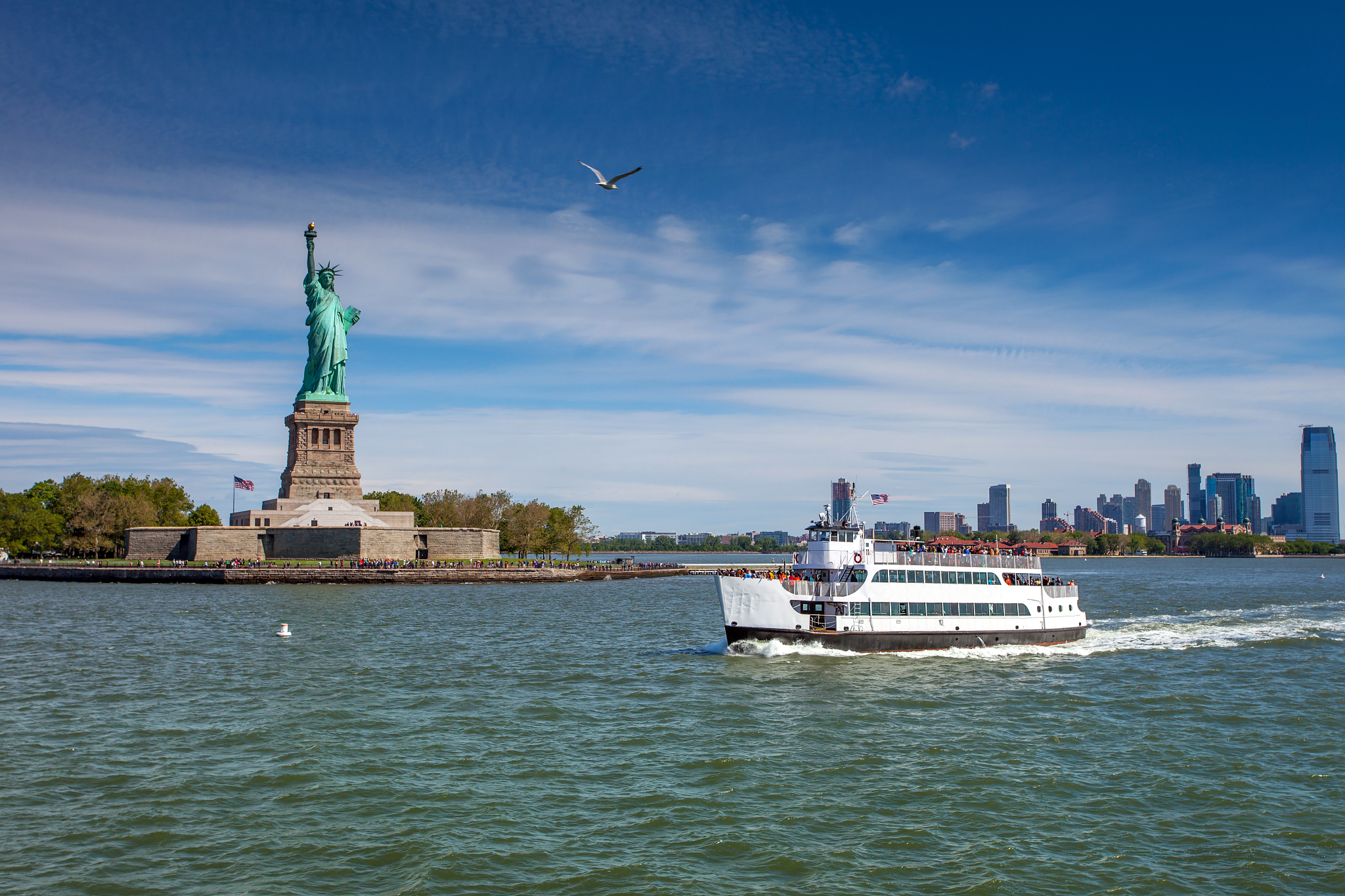 a cruise boat in front of the liberty island and the statue of l