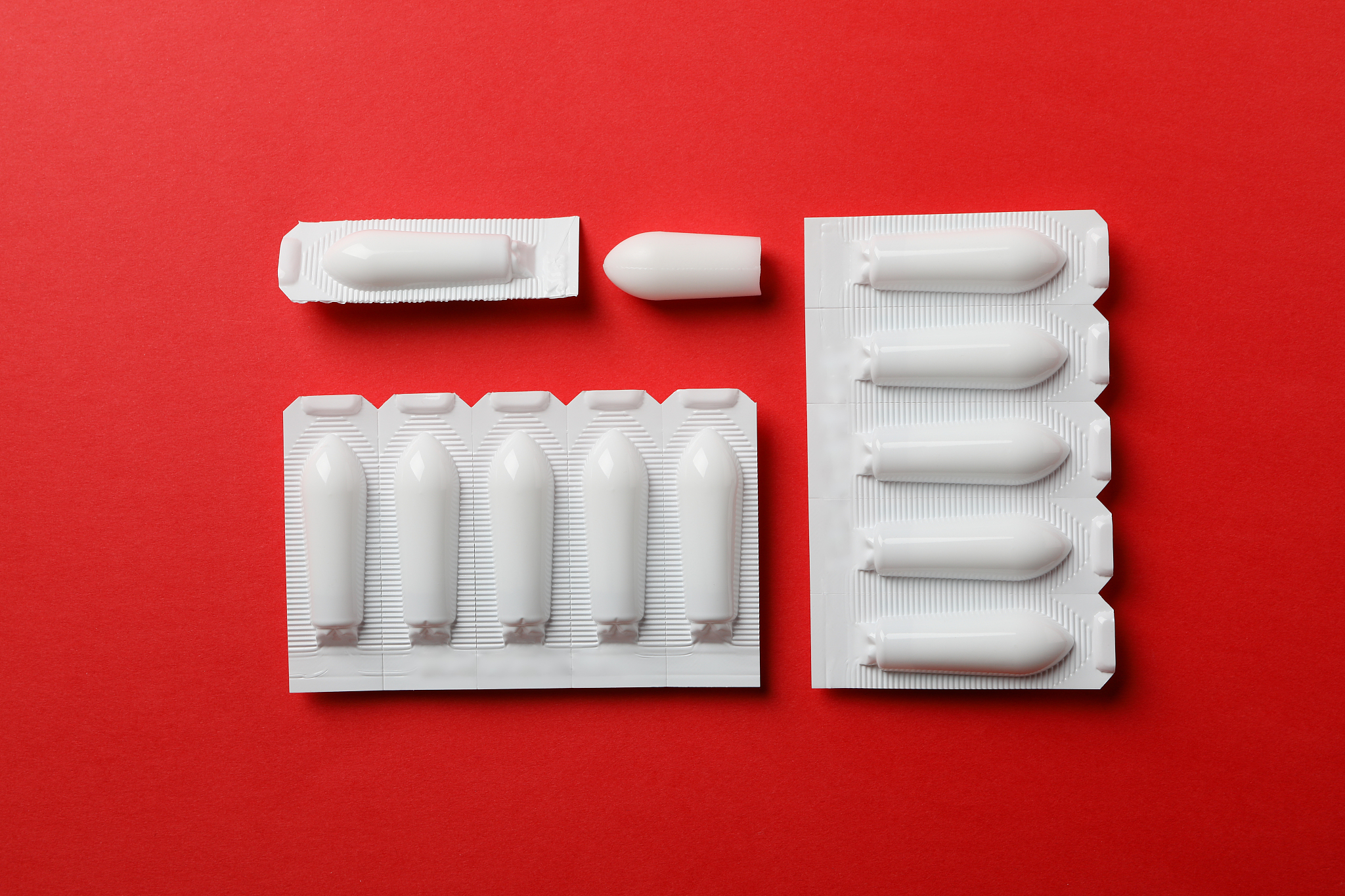anal or vaginal candles on red background, top view