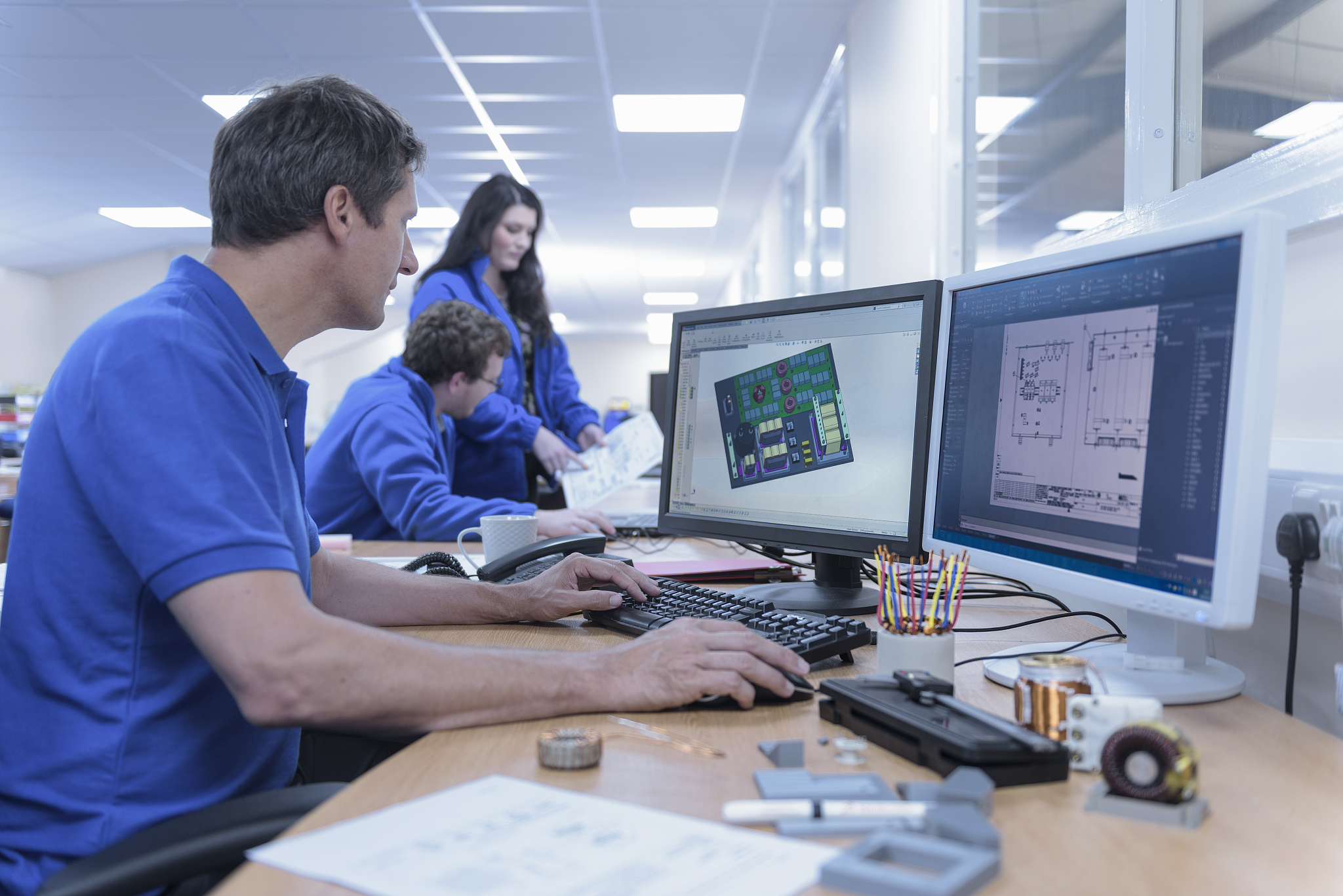 electronics designers with cad imagery in electronics factory