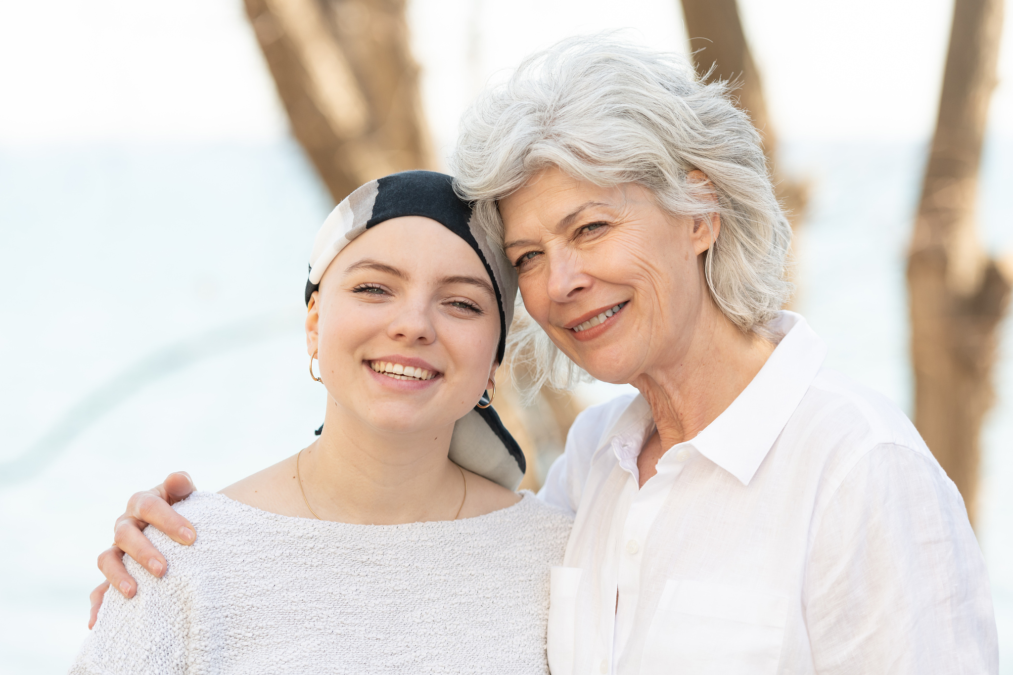 senior mother embracing her daughter with cancer