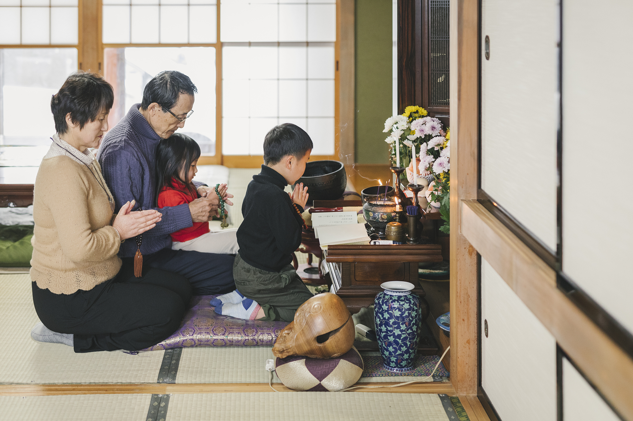 japanese multi generation family praying in front of family budd