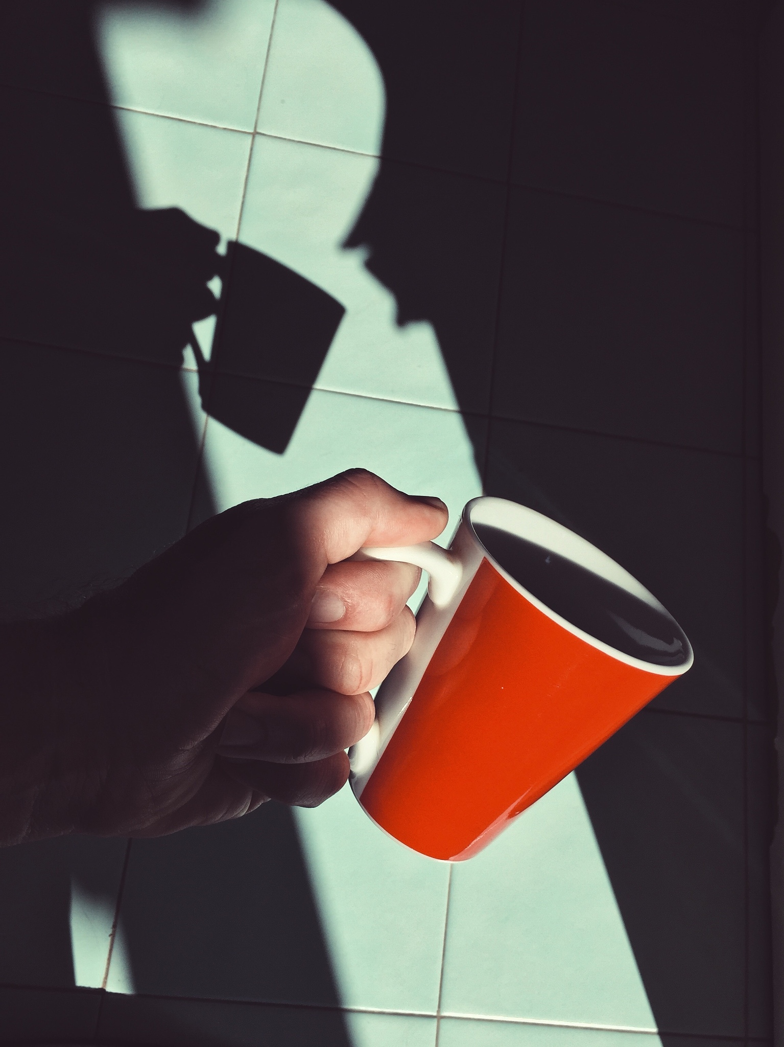 close-up of cropped hand holding cup over floor