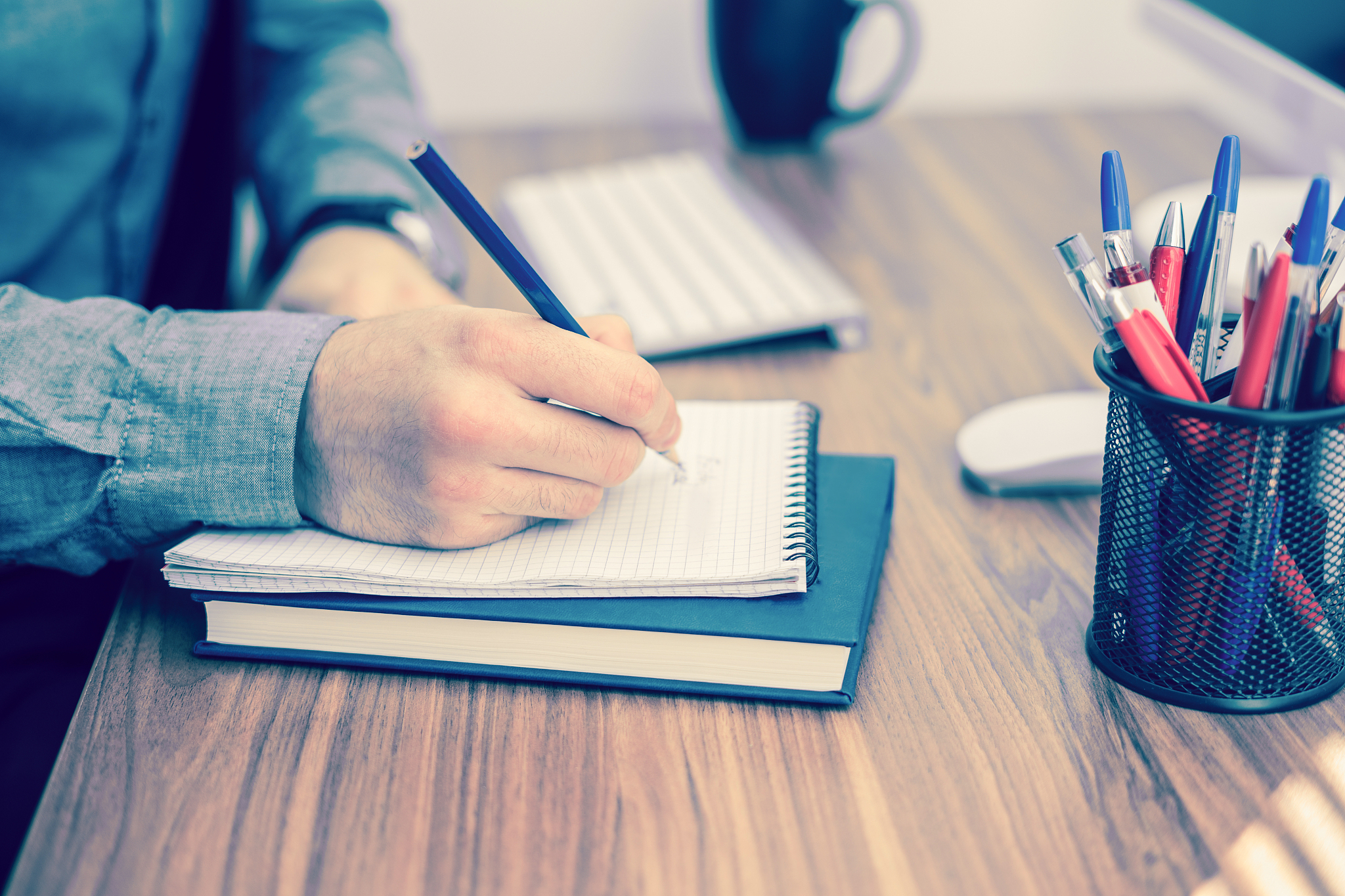 hand writing in notebook on wooden table