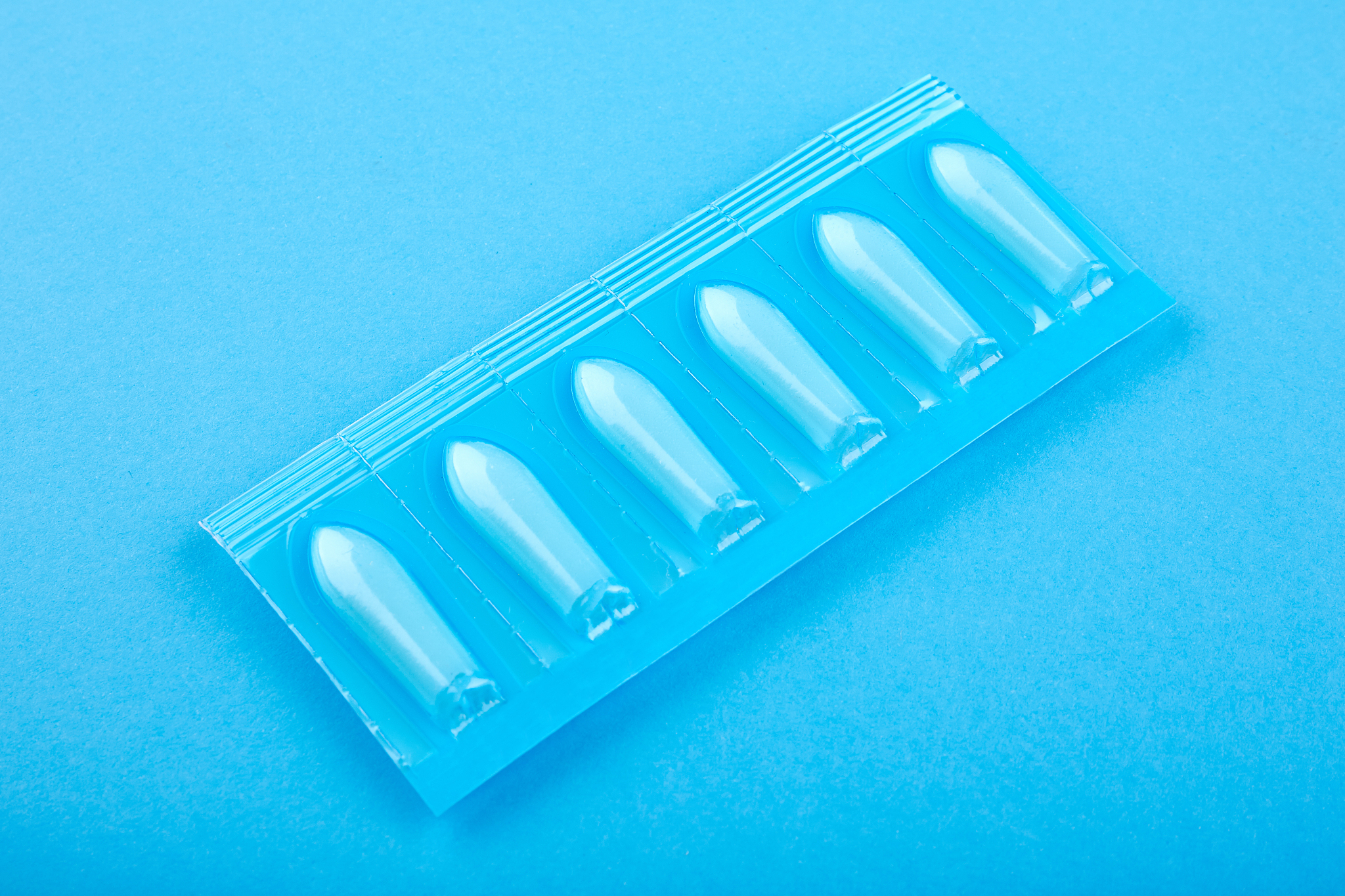 plastic package with suppository on blue background