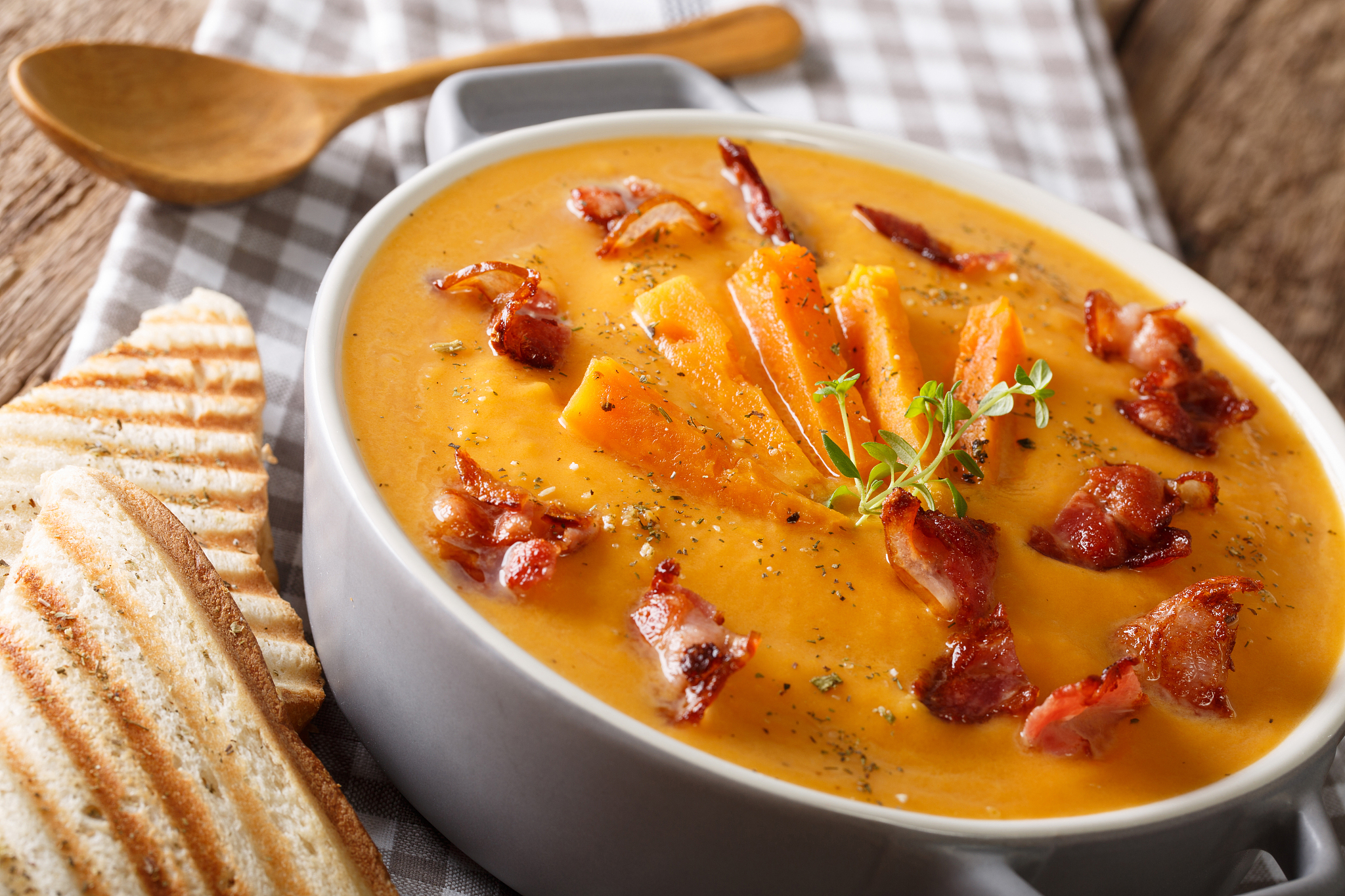 sweet potato soup with bacon and herbs in a pan macro. horizonta