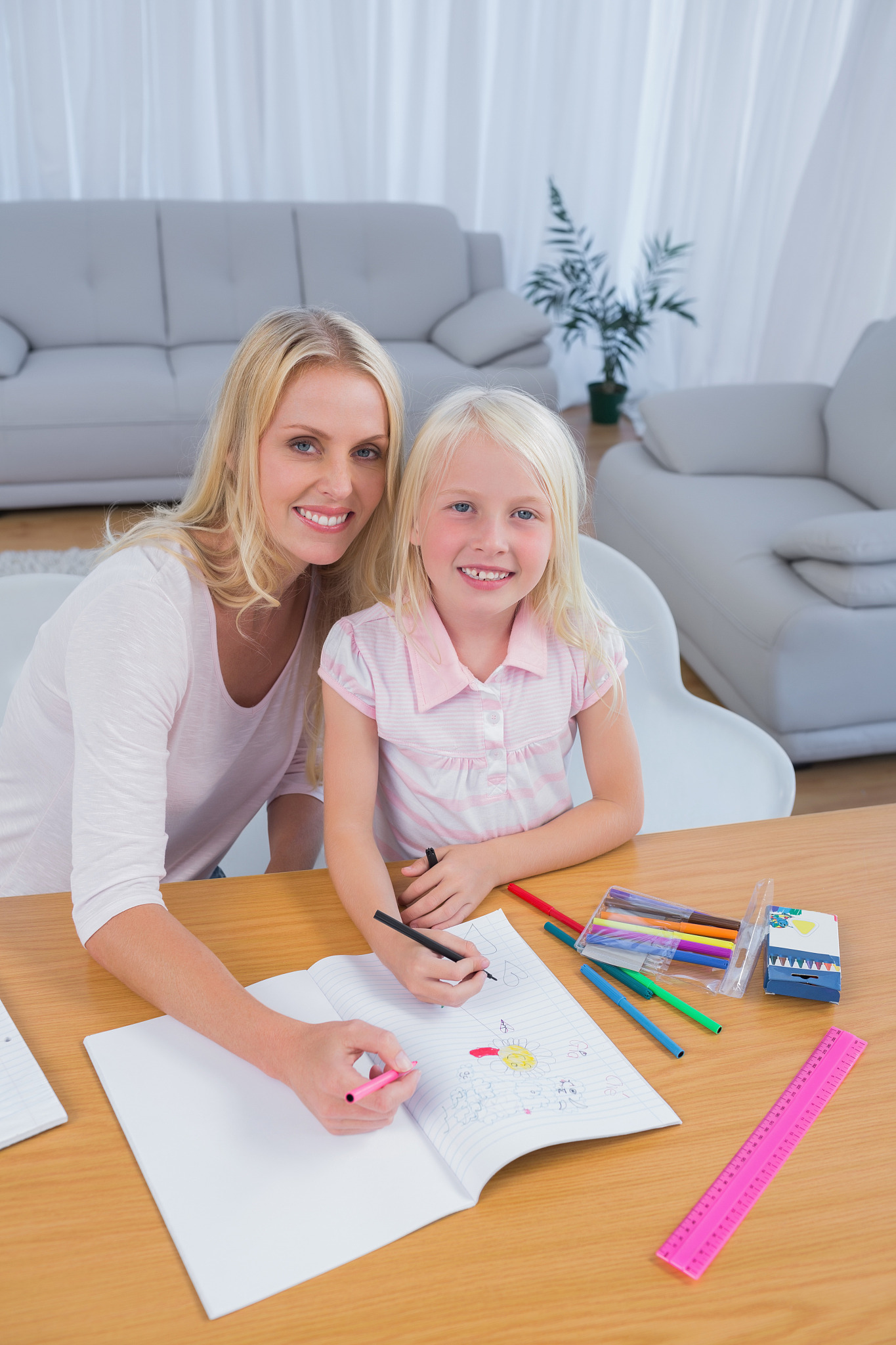 smiling mother drawing with her little girl in the living room