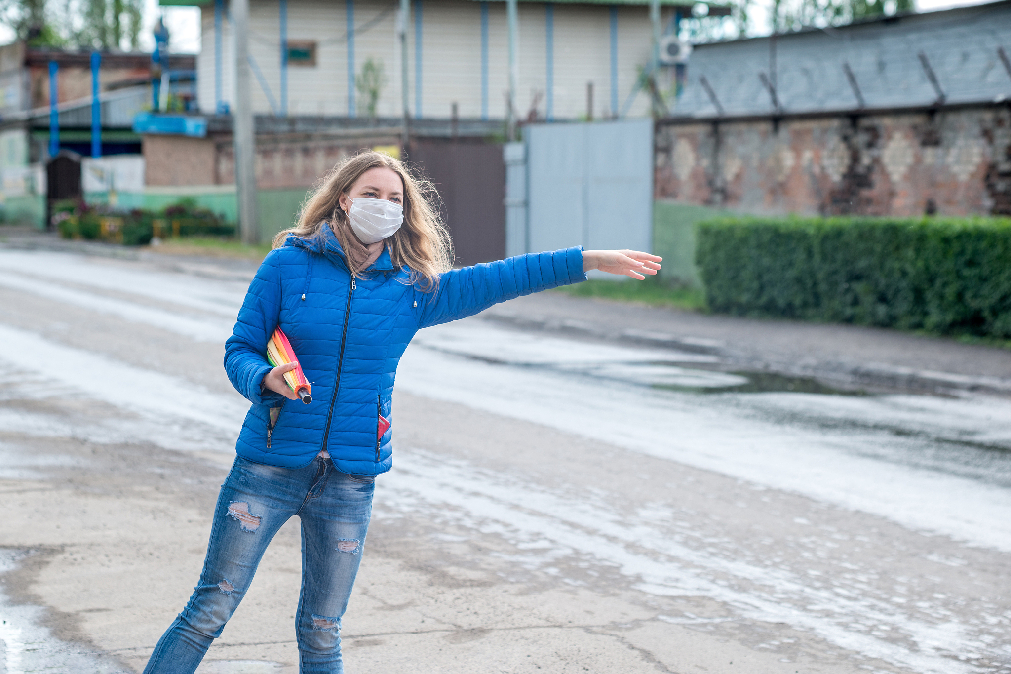 caucasian girl in a protective mask hails taxi on an empty stree