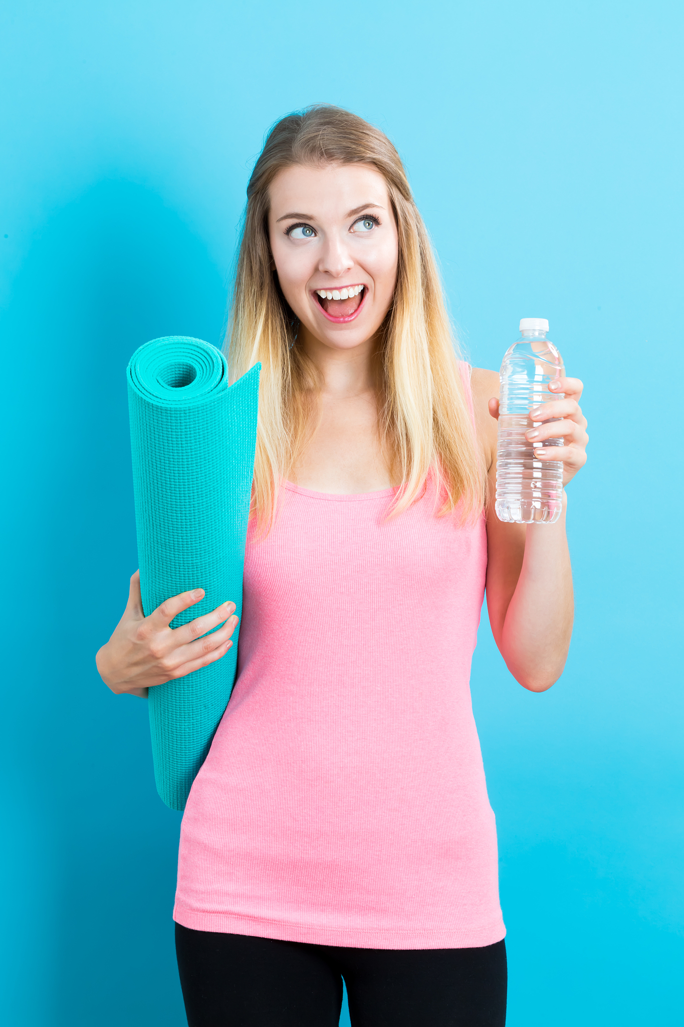 woman holding yoga mat and water bottle