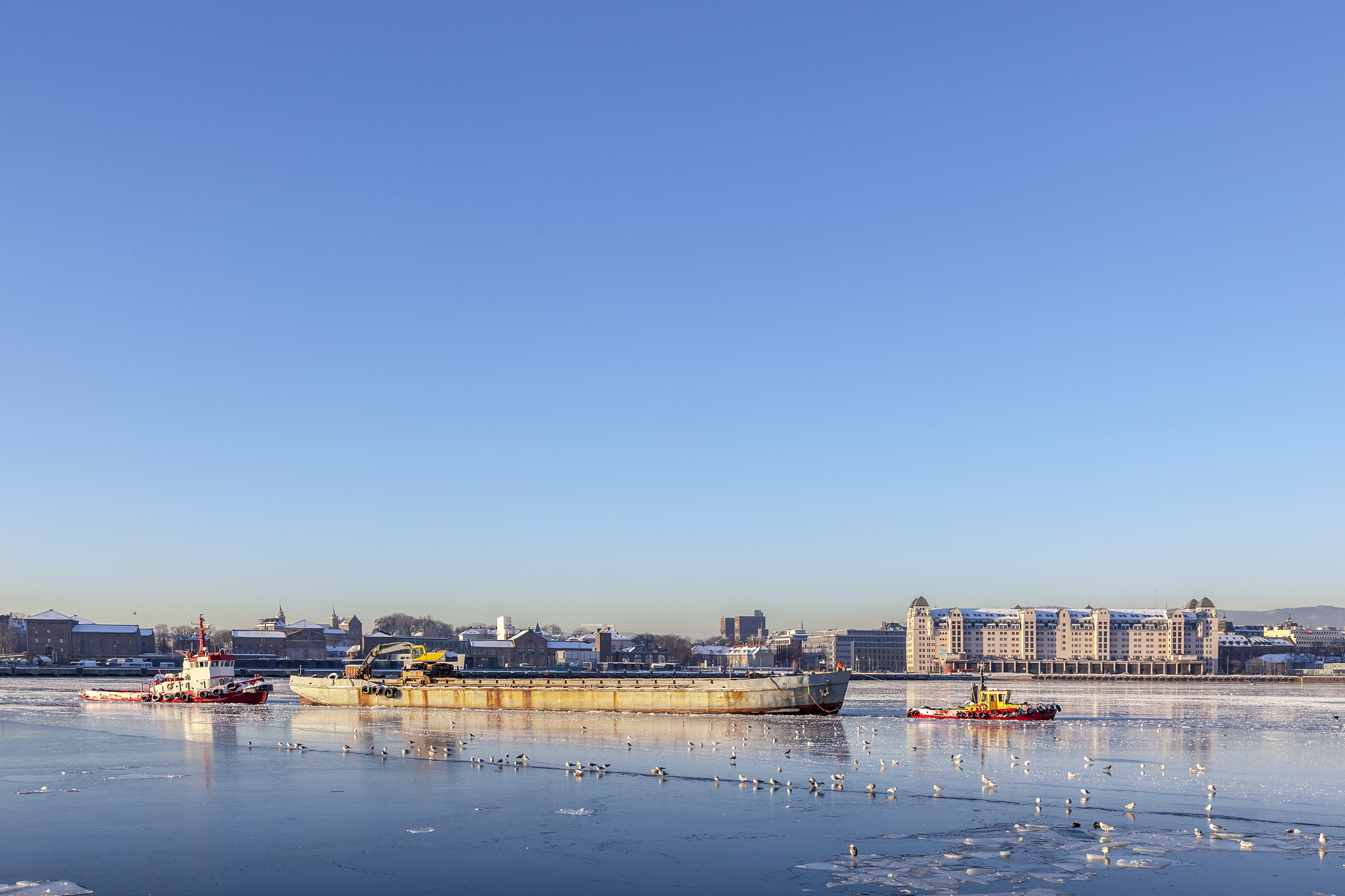 tugs in oslo harbor in winter  at sunset.