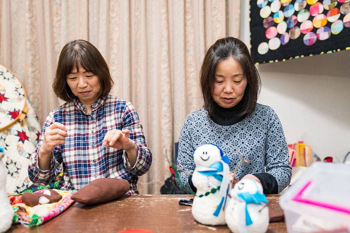 一位年长妇女在她的家中缝纫和制作工艺品