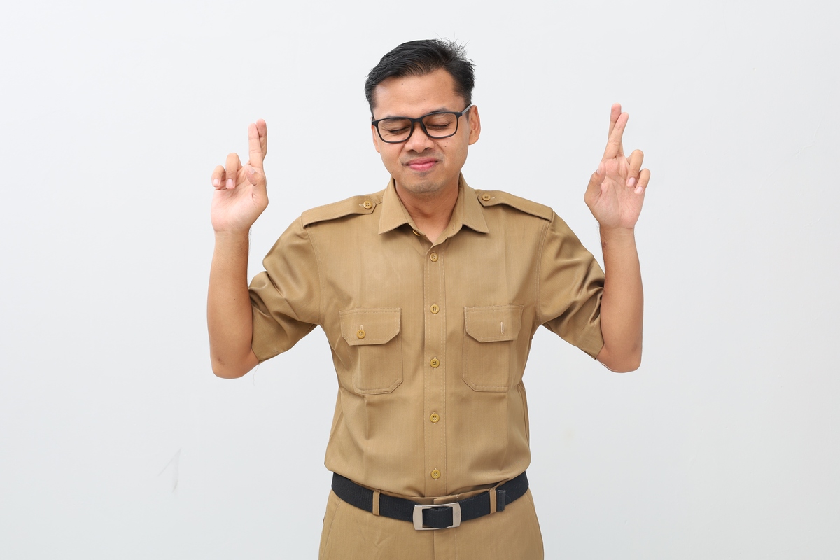 一位快乐的印度尼西亚年轻男子身穿政府制服,闭着眼睛
