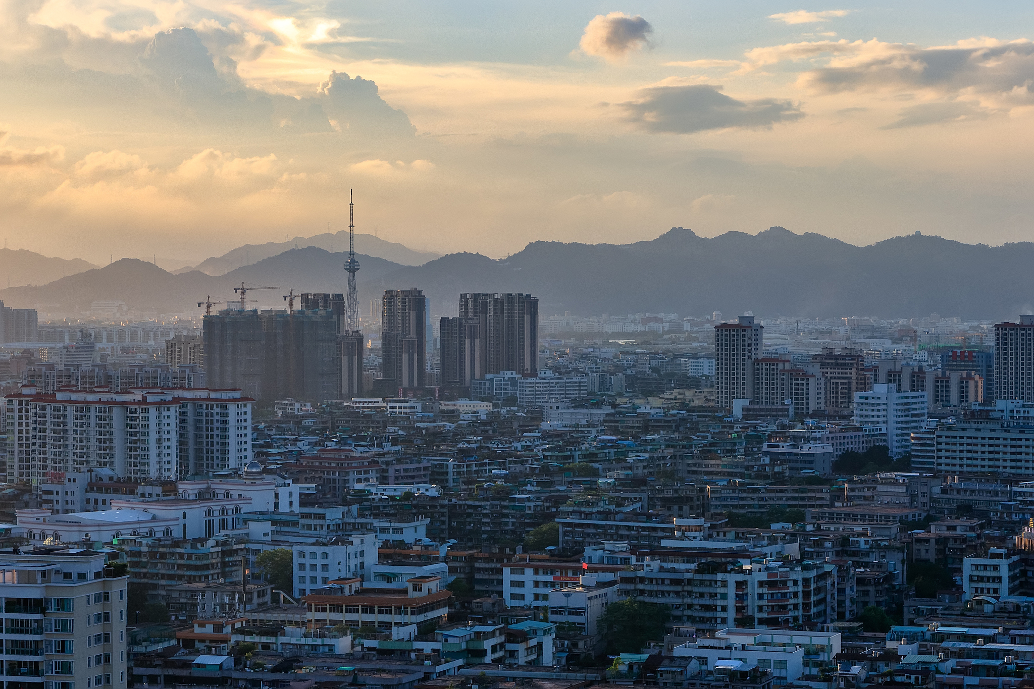 aerial view of buildings in city against cloudy sky