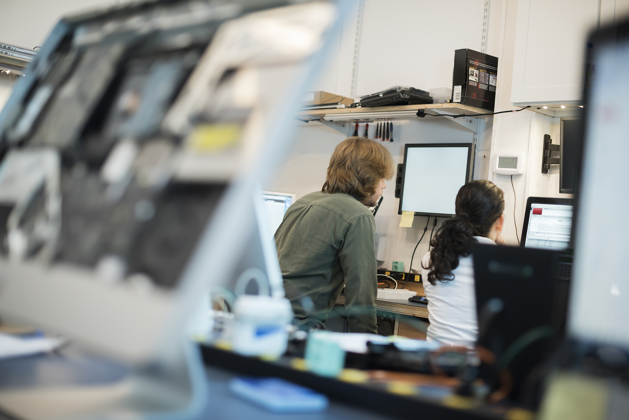 computer repair shop. two people seated using screens, and compu