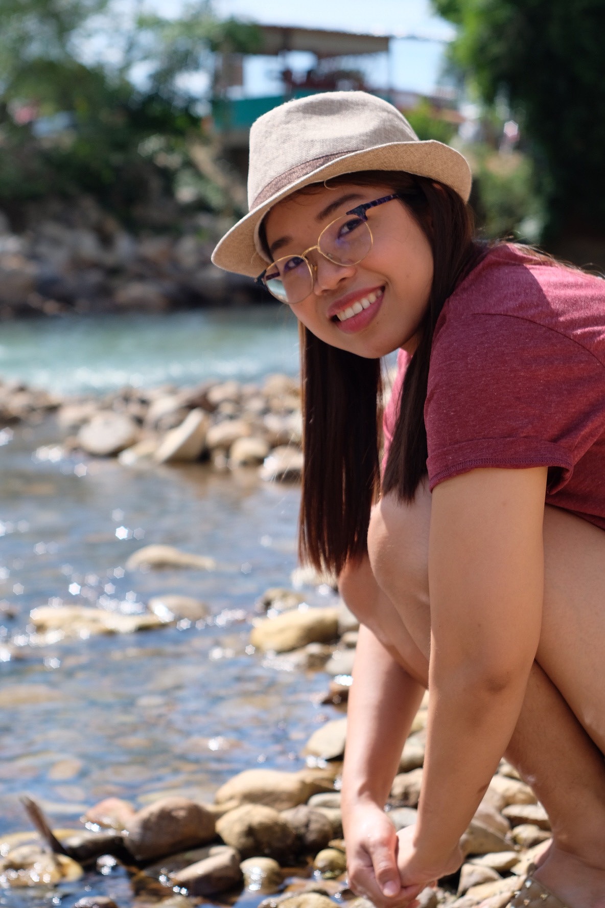 portrait of smiling woman on stones by flowing river