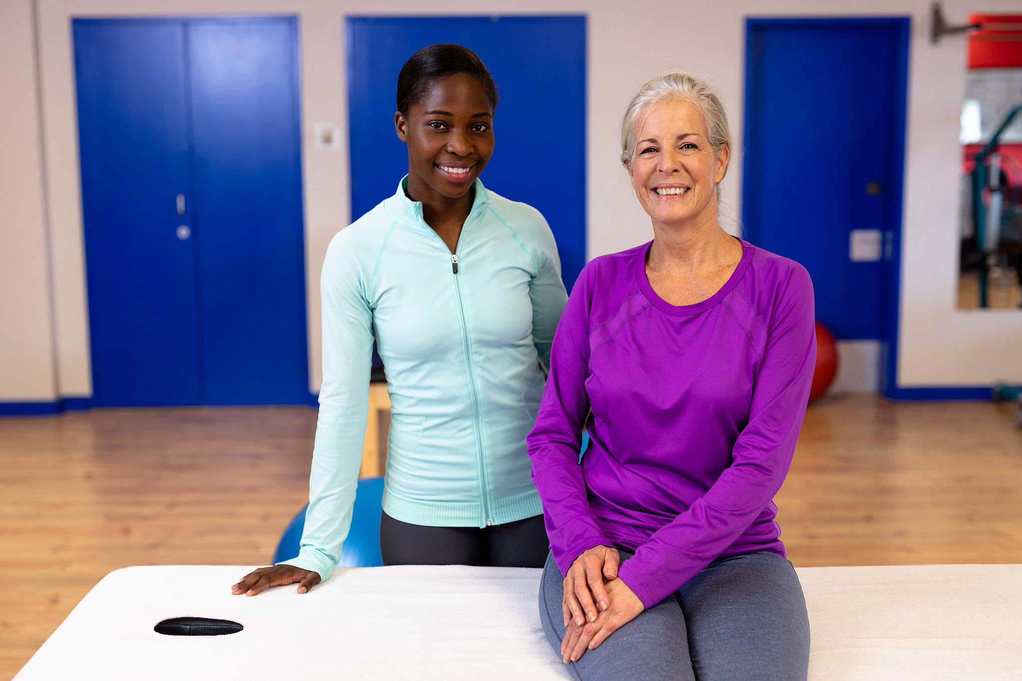 female physiotherapist and active senior woman looking at camera