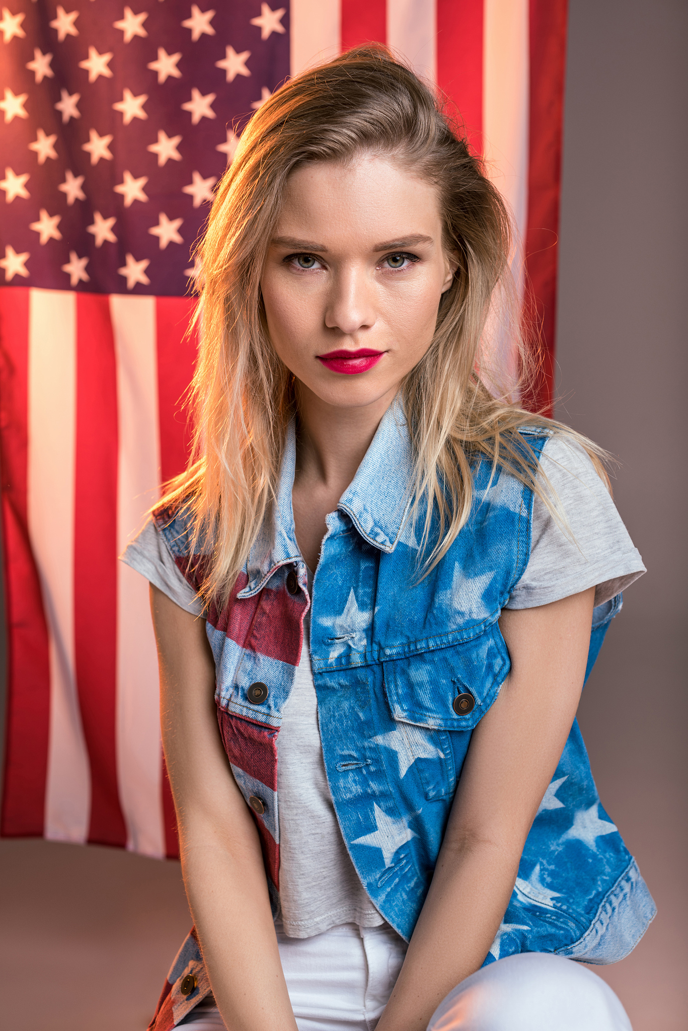 woman looking at camera in front of usa flag, independence day o