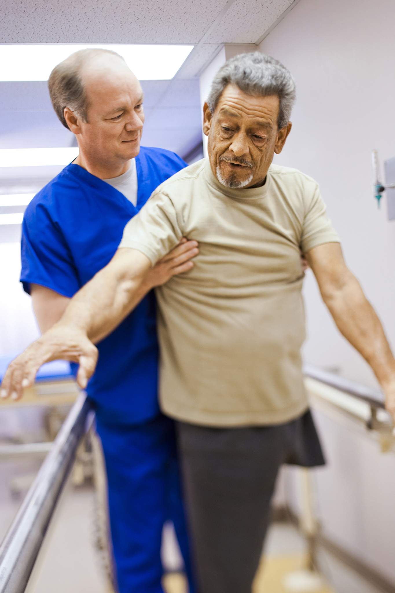 physical therapist assisting an older man with one leg in walkin