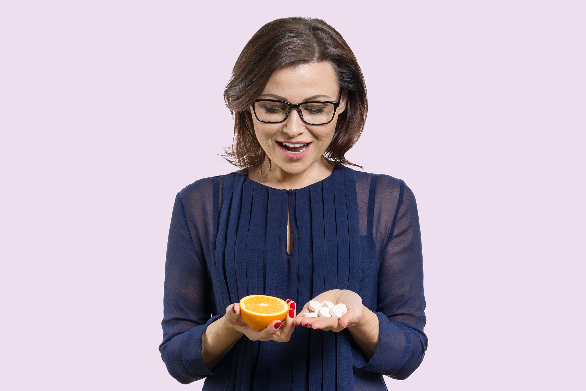 woman holds natural vitamin-orange in one hand and synthetic vit