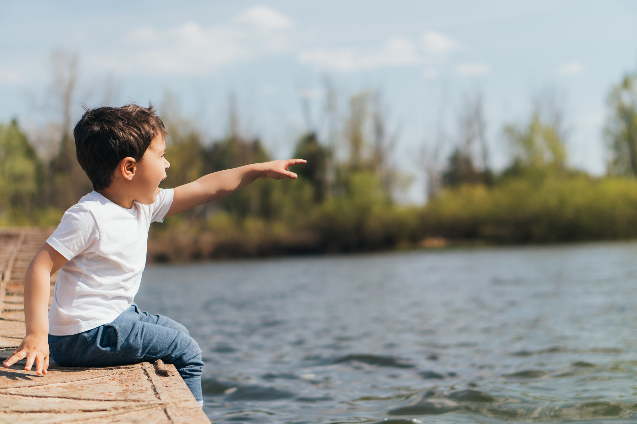 profile of emotional boy pointing with finger while sitting near