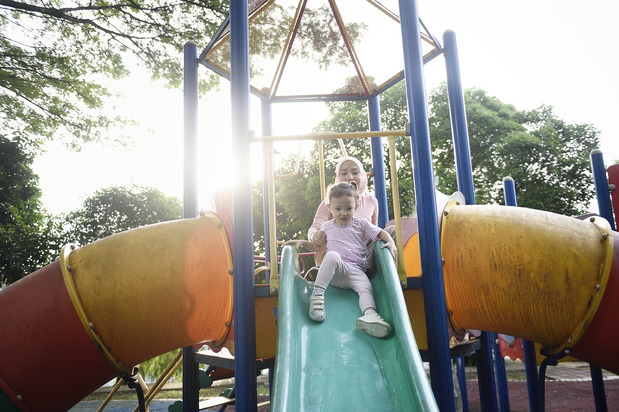 malay woman with her child on a playground slide