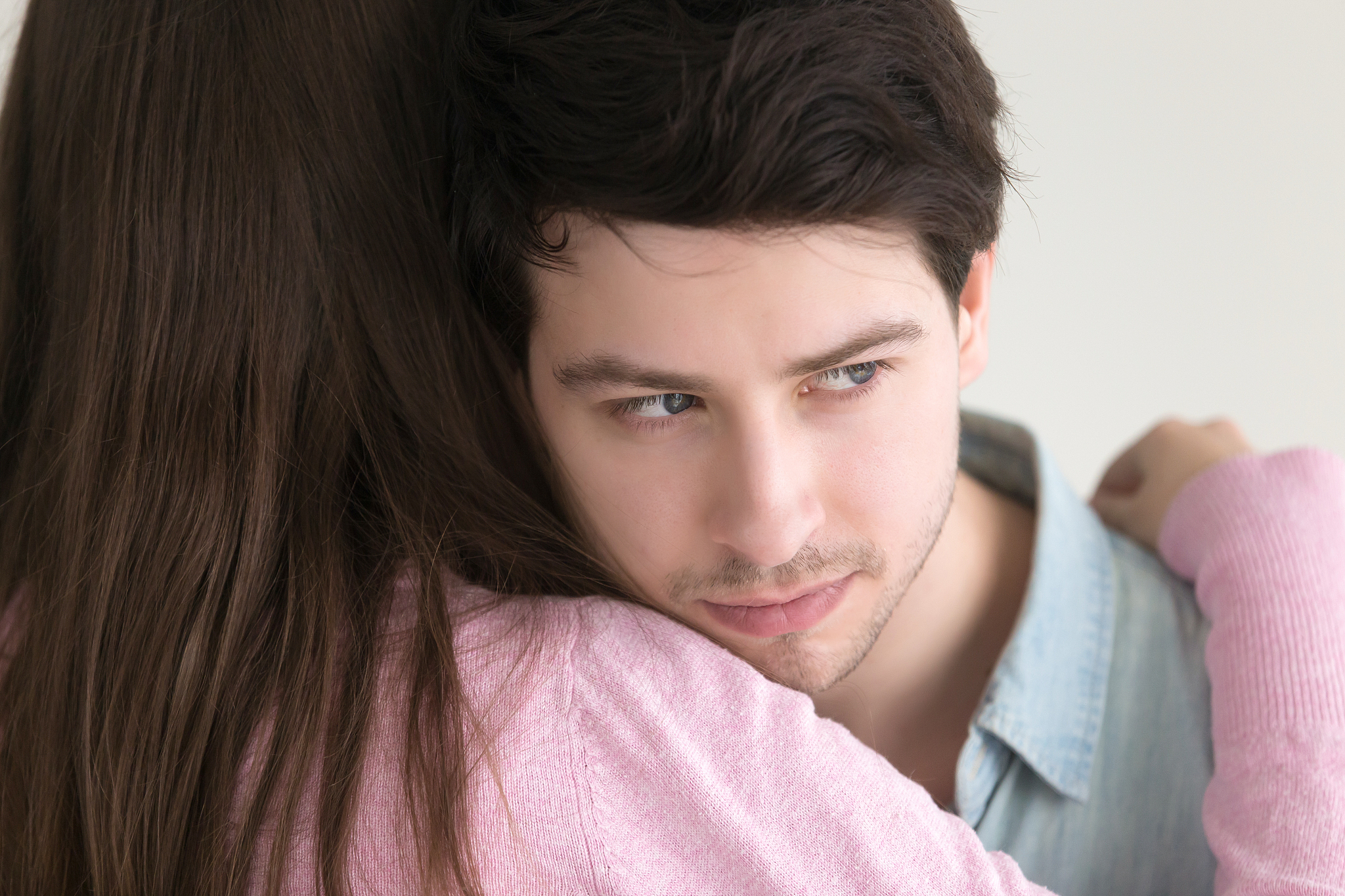 thoughtful young man embracing lady looking away, lost in though